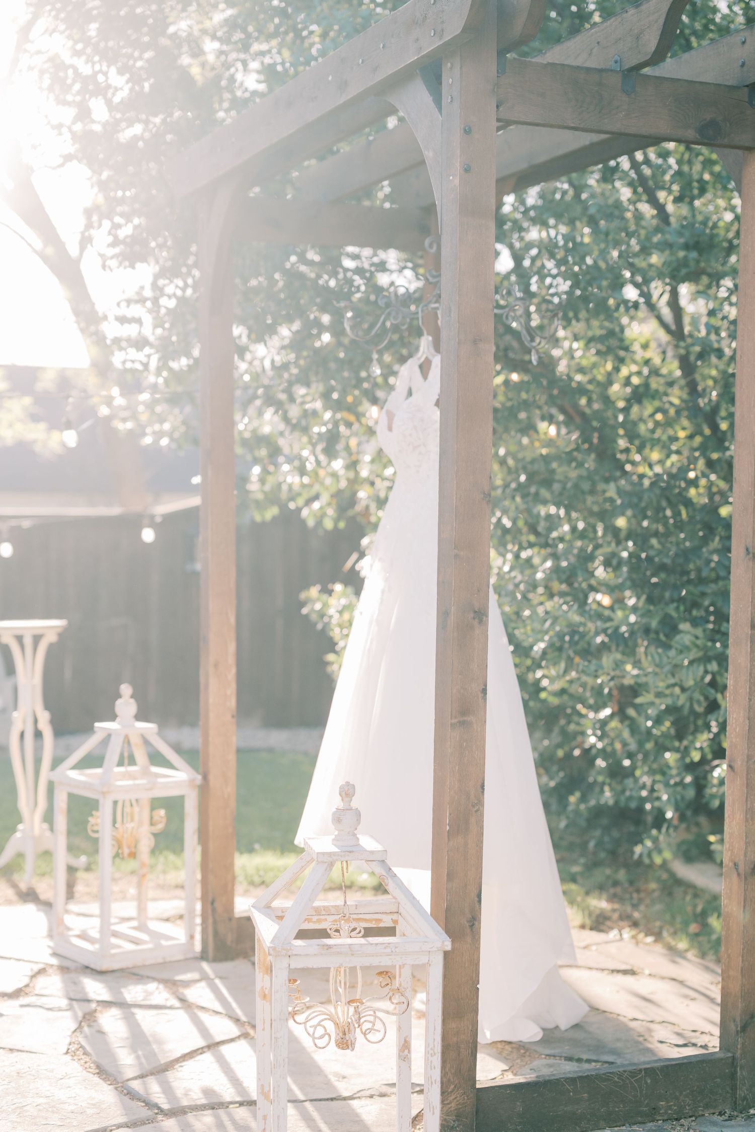 Elegant white lanterns and flowing curtains create a romantic outdoor patio setting with natural sunlight filtering through.