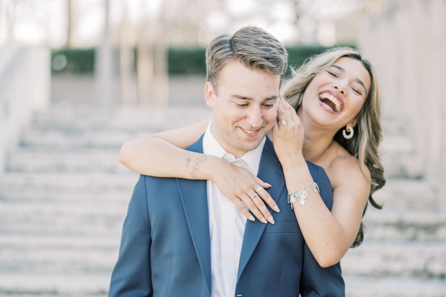 A couple shares a joyful candid moment together while laughing on stone steps outdoors.