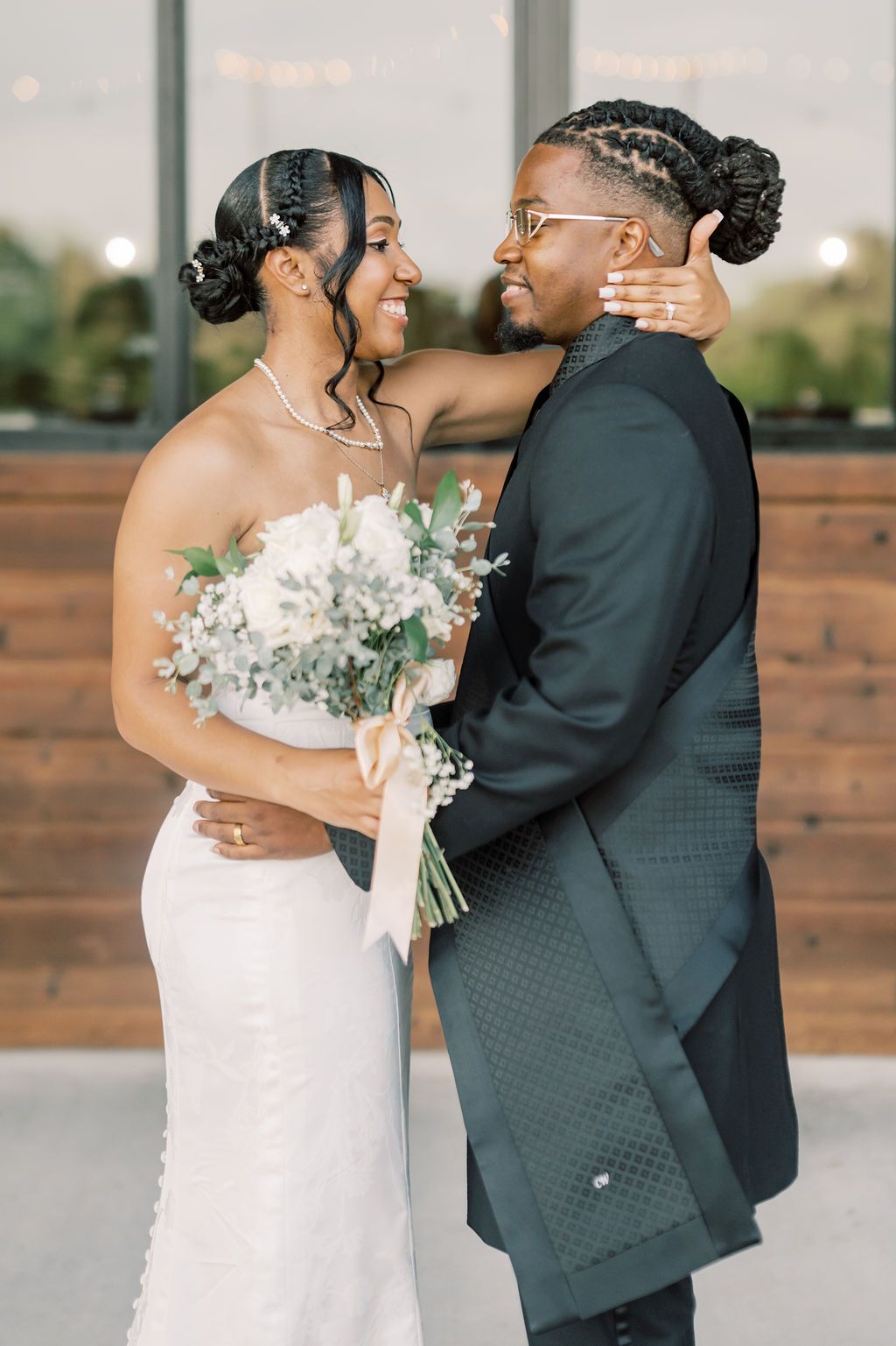 A joyful Black couple shares an intimate wedding moment, bride in white gown holding bouquet, groom in dark suit.