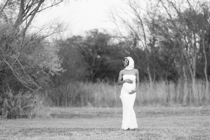 A flowing white dress moves gracefully across a serene field with bare trees in the background.