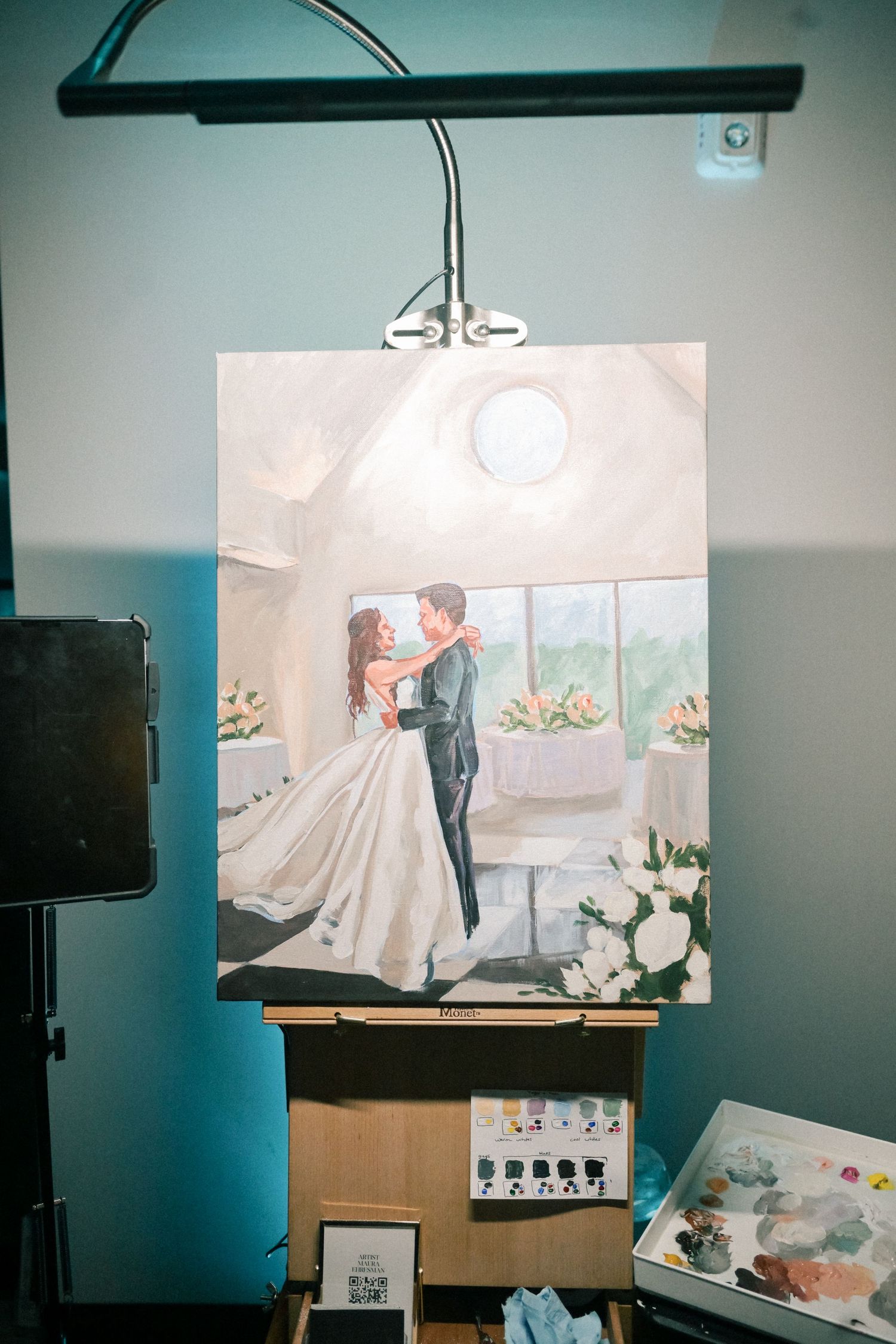 Live wedding painter creating a portrait of bride and groom sharing first dance on easel.