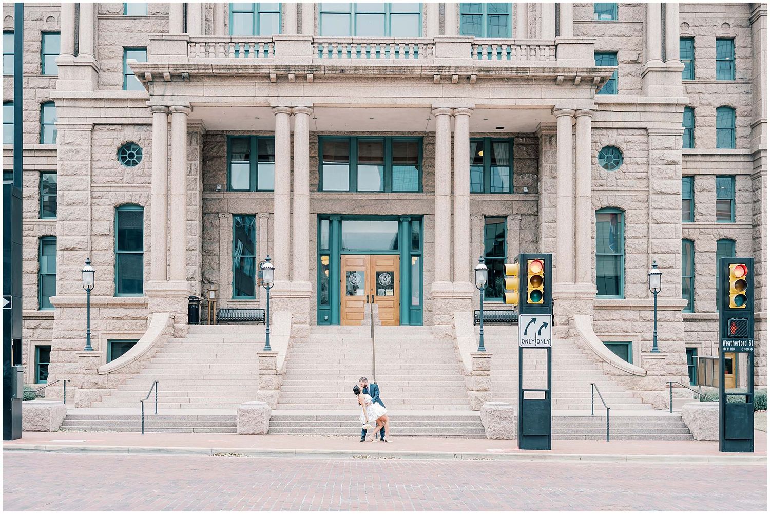 Exterior view of a grand neoclassical building entrance with stone columns and steps.