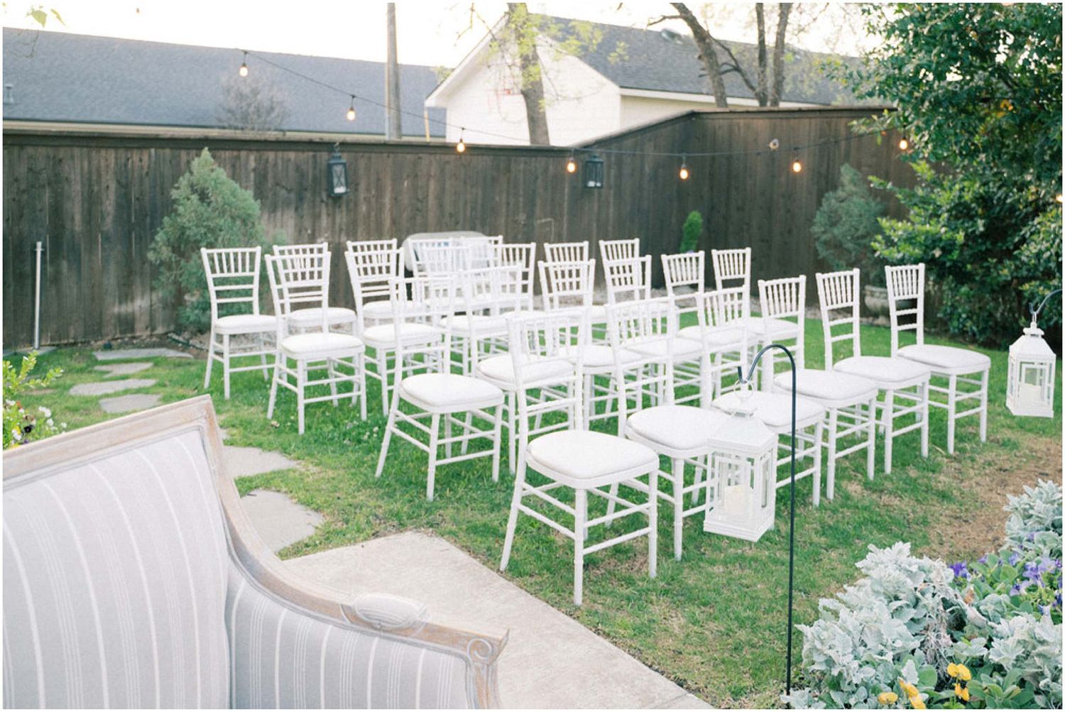 White wooden chairs arranged in rows on a grassy lawn for an outdoor wedding ceremony.