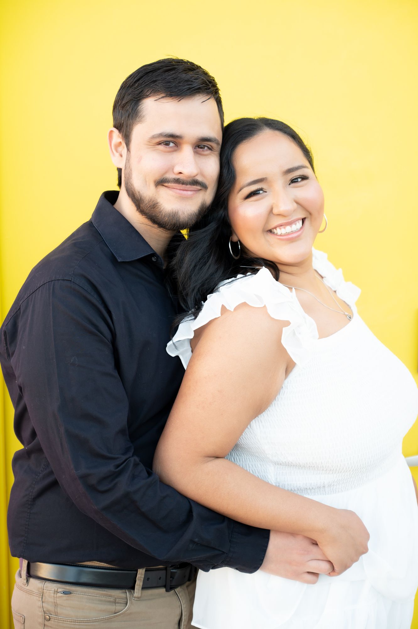Couple embracing against yellow background in series of romantic poses wearing black and white outfits.