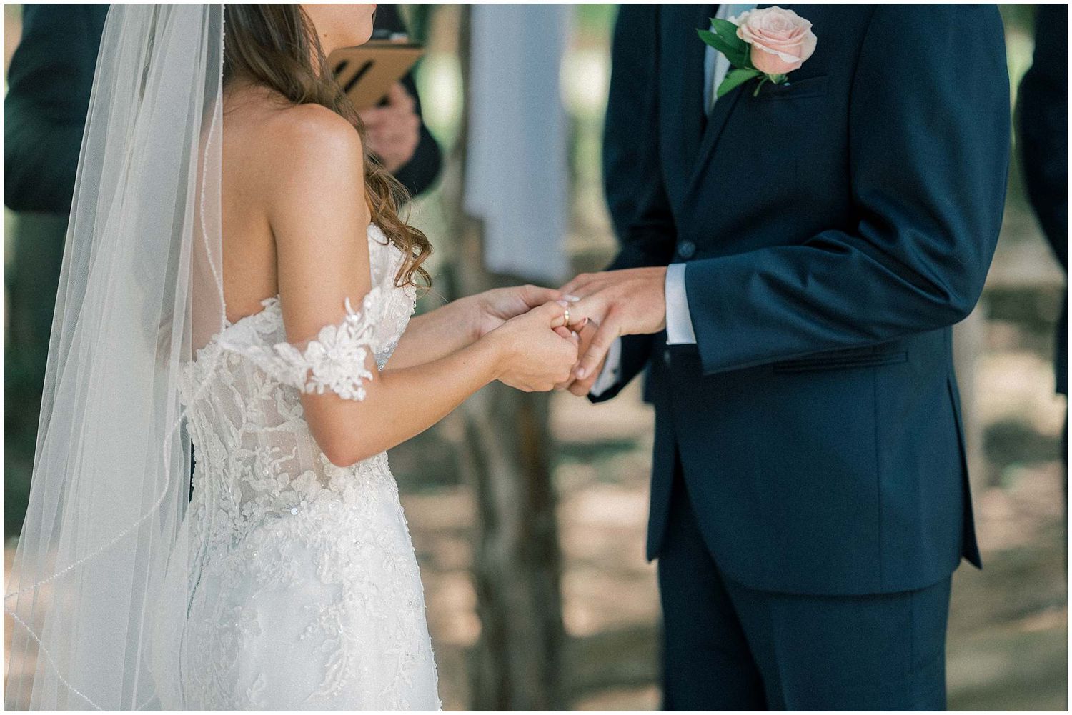 Close-up shots of a bride and groom exchanging wedding rings during an outdoor ceremony.
