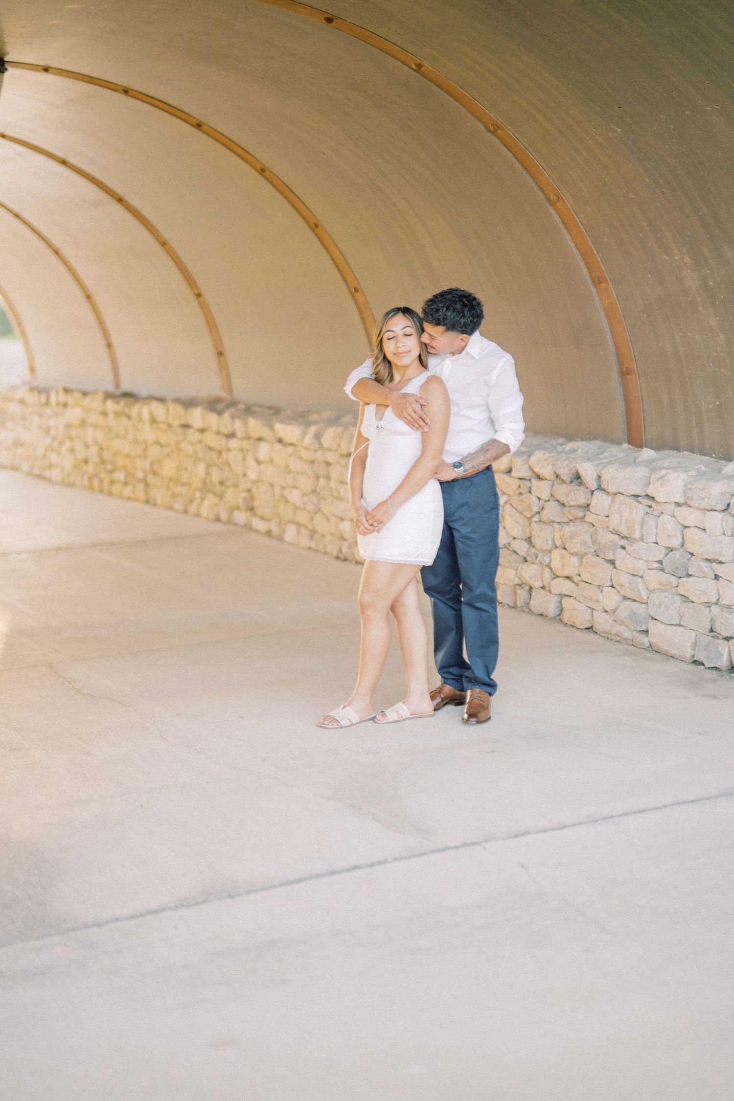 Romantic couple sharing a tender moment in a curved stone tunnel during engagement photos.