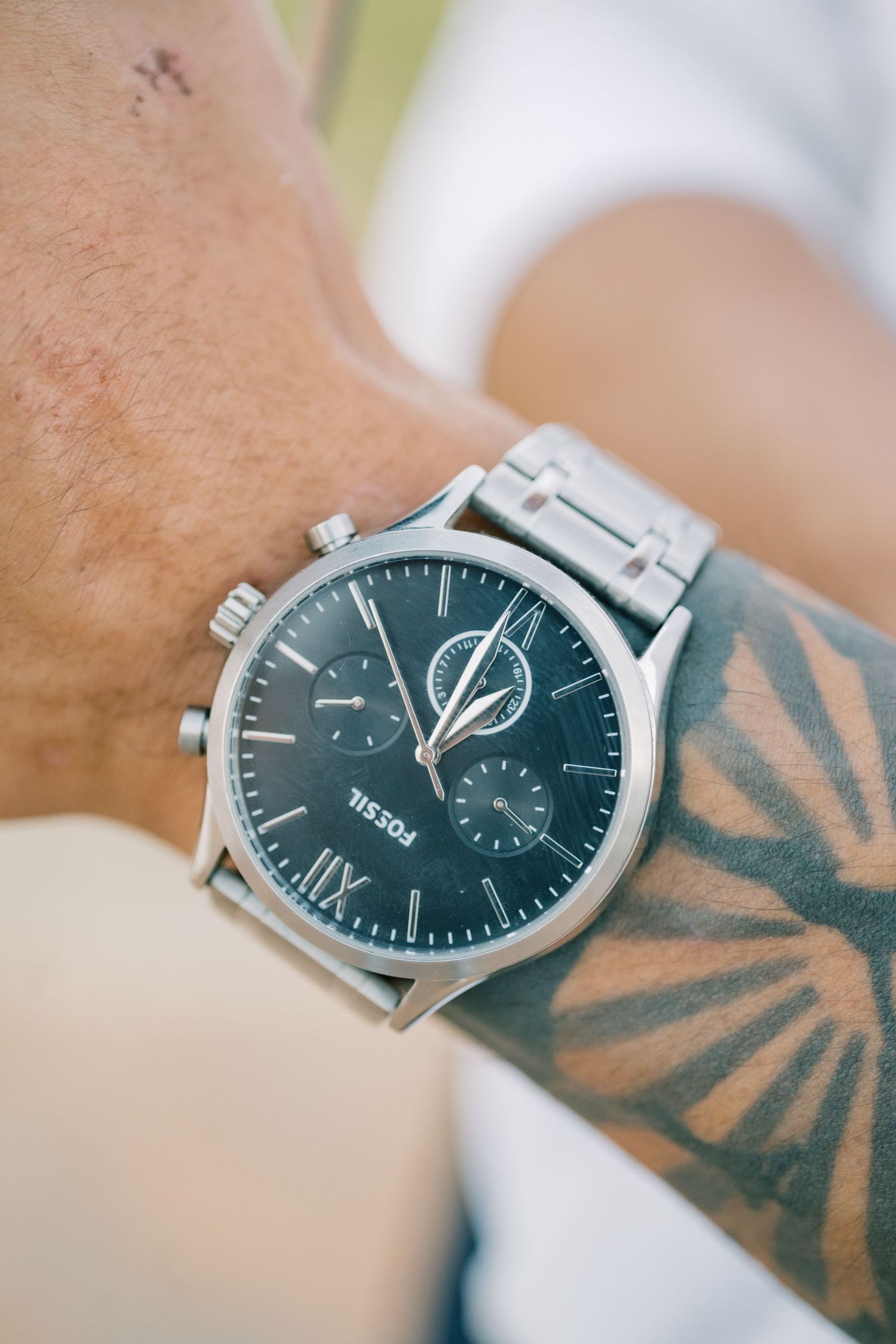 Close-up of a mans wrist featuring a Fossil chronograph watch and geometric tattoo design.