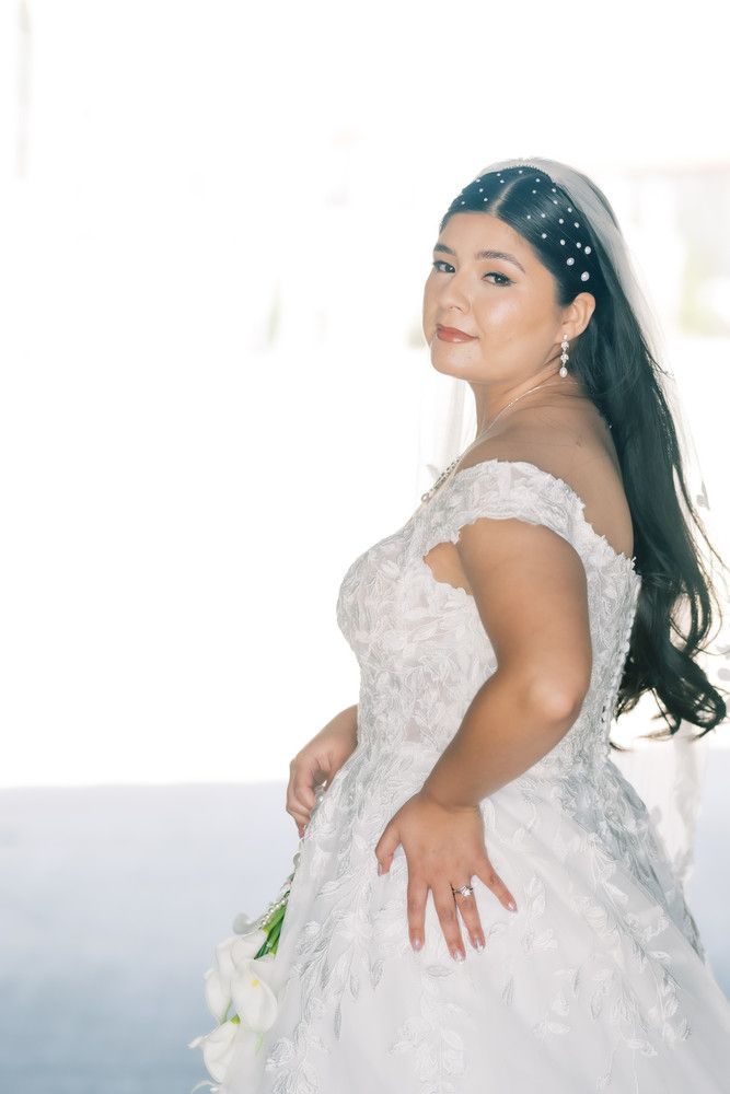 An elegant white beaded wedding gown is showcased in a bright, airy setting with delicate details.