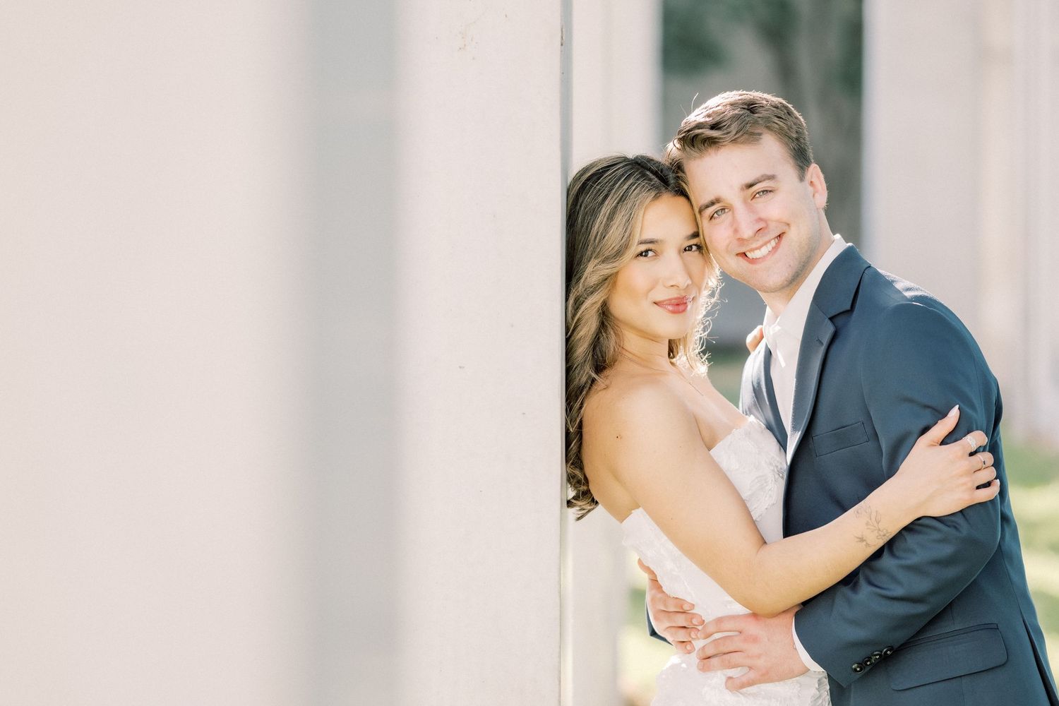 A happy couple embraces and smiles together during their outdoor wedding photo session.