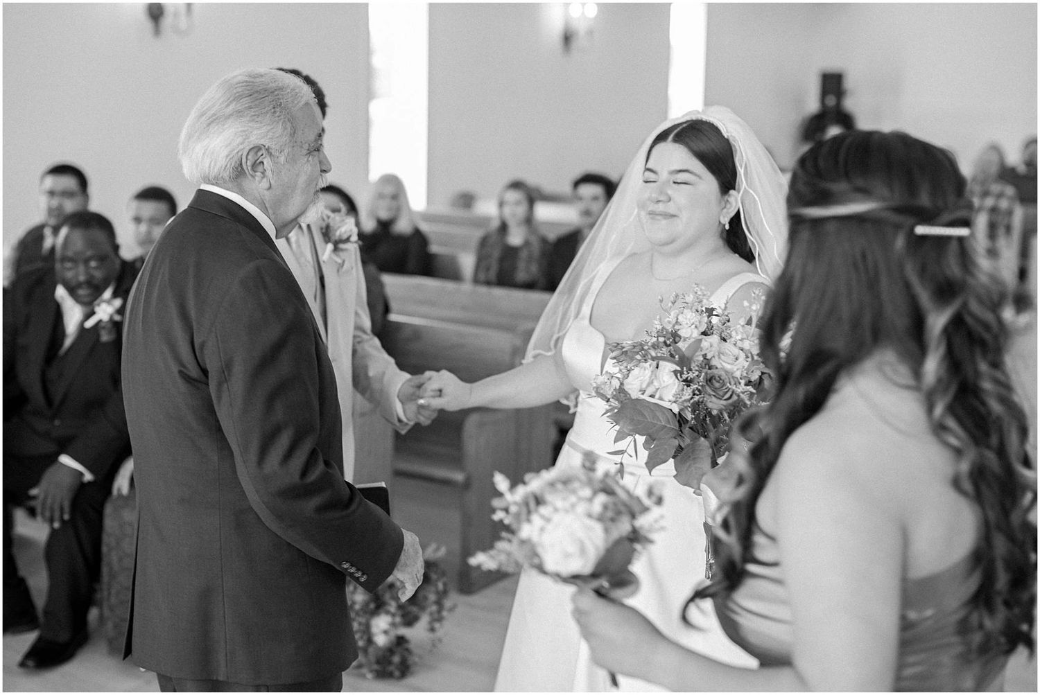 Wedding party exchanging vows during ceremony in bright church setting.