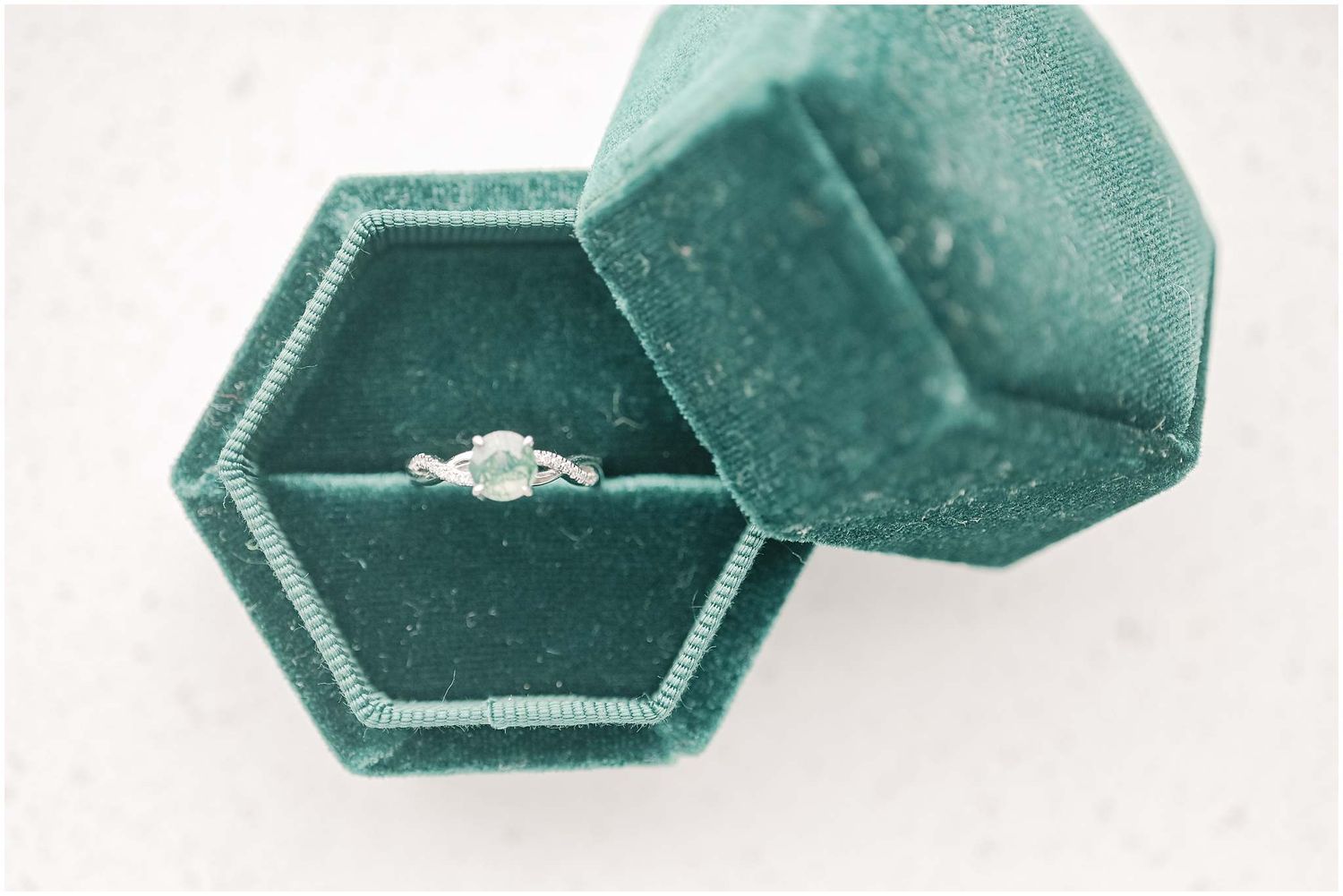 A green velvet ring box shown from multiple angles with a sparkling diamond engagement ring inside.