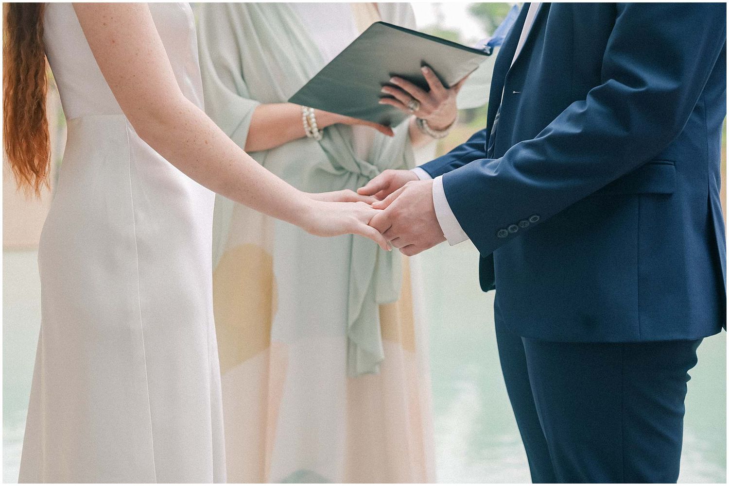 Close-up of wedding ring exchange ceremony with white dress and navy suit.