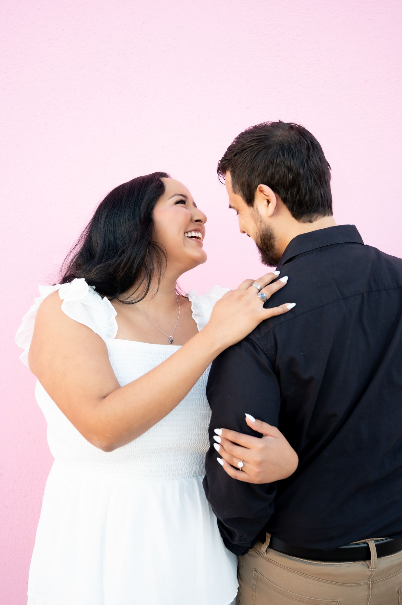 A joyful couple shares laughter and embraces against a soft pink background in sequential shots.