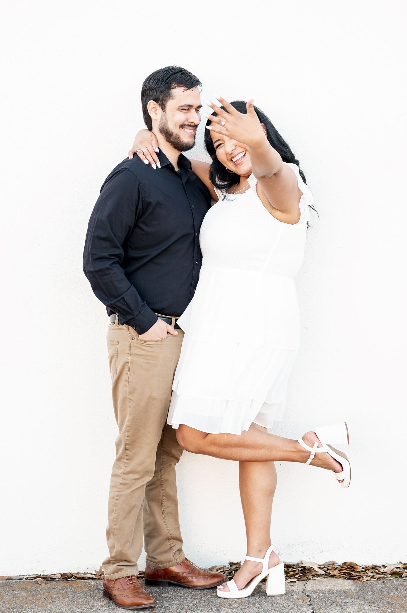 Romantic couple poses together showing affection in a clean white studio setting.