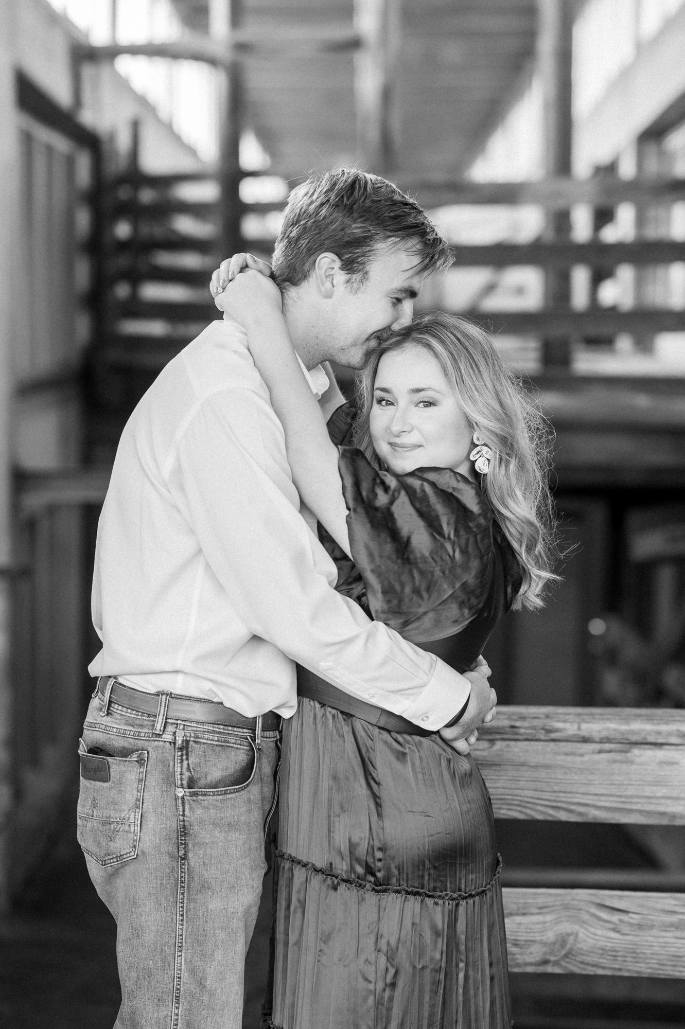 Black and white photo of couple sharing romantic moments by wooden railings.