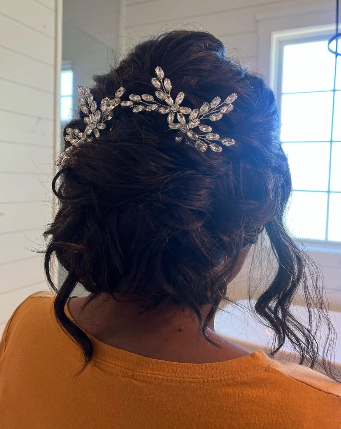 Woman with dark hair in elegant updo adorned with sparkling crystal rhinestone floral hair vine accessory.