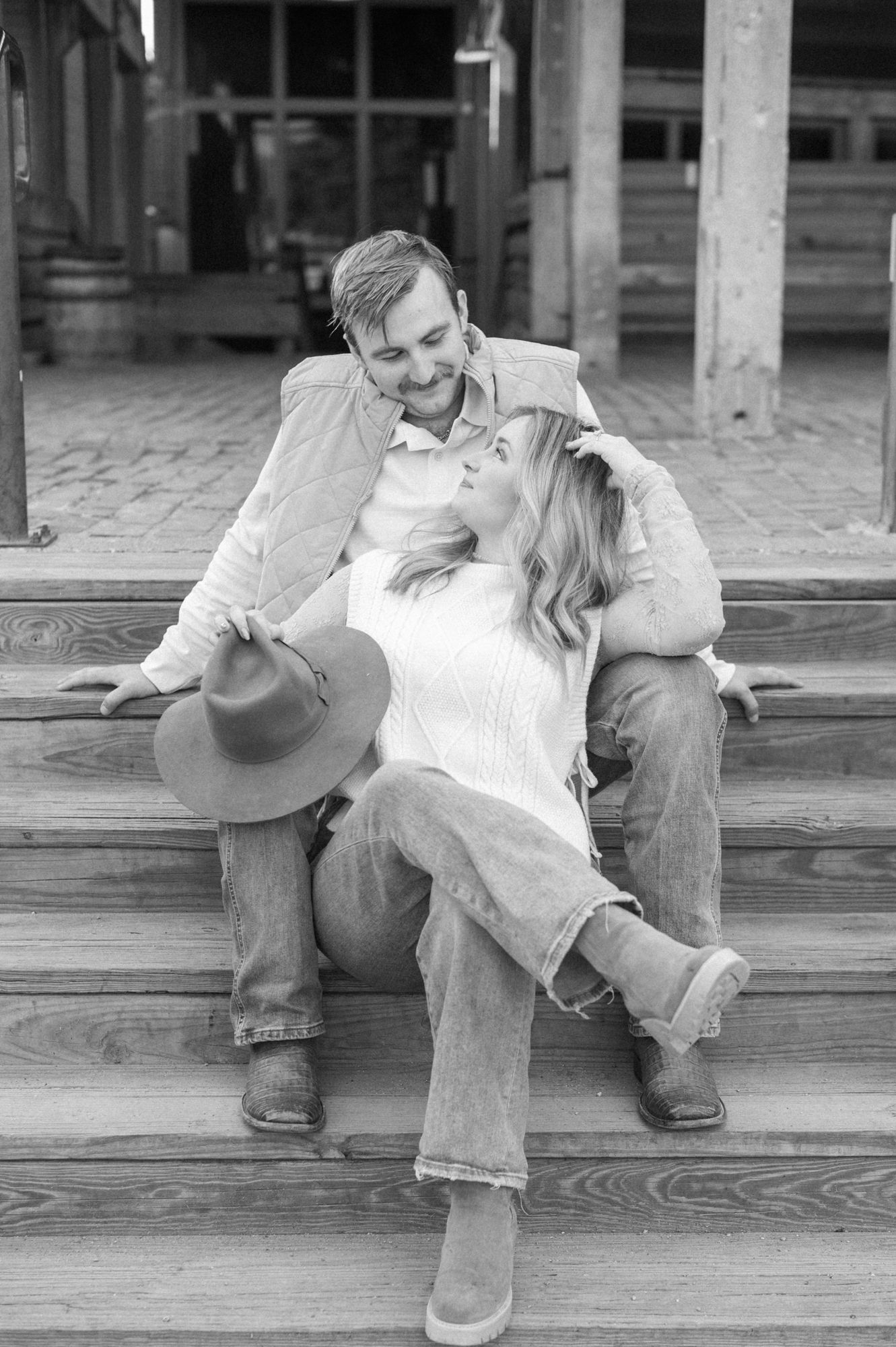 A romantic couple in casual attire sharing an intimate moment while sitting on wooden steps.