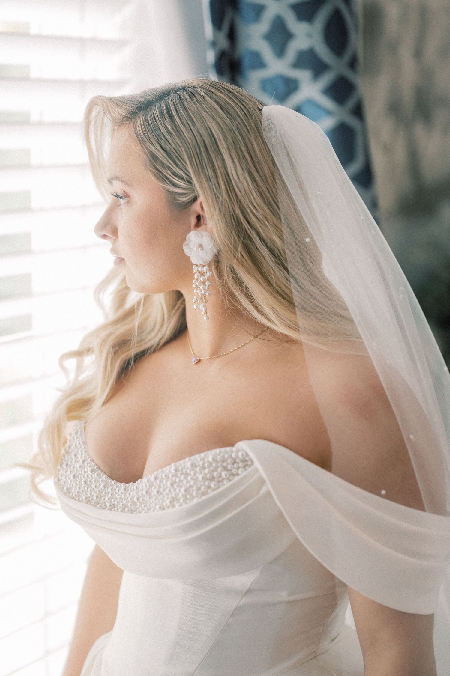 Bride wearing elegant lace wedding dress and veil captured in romantic side profile.