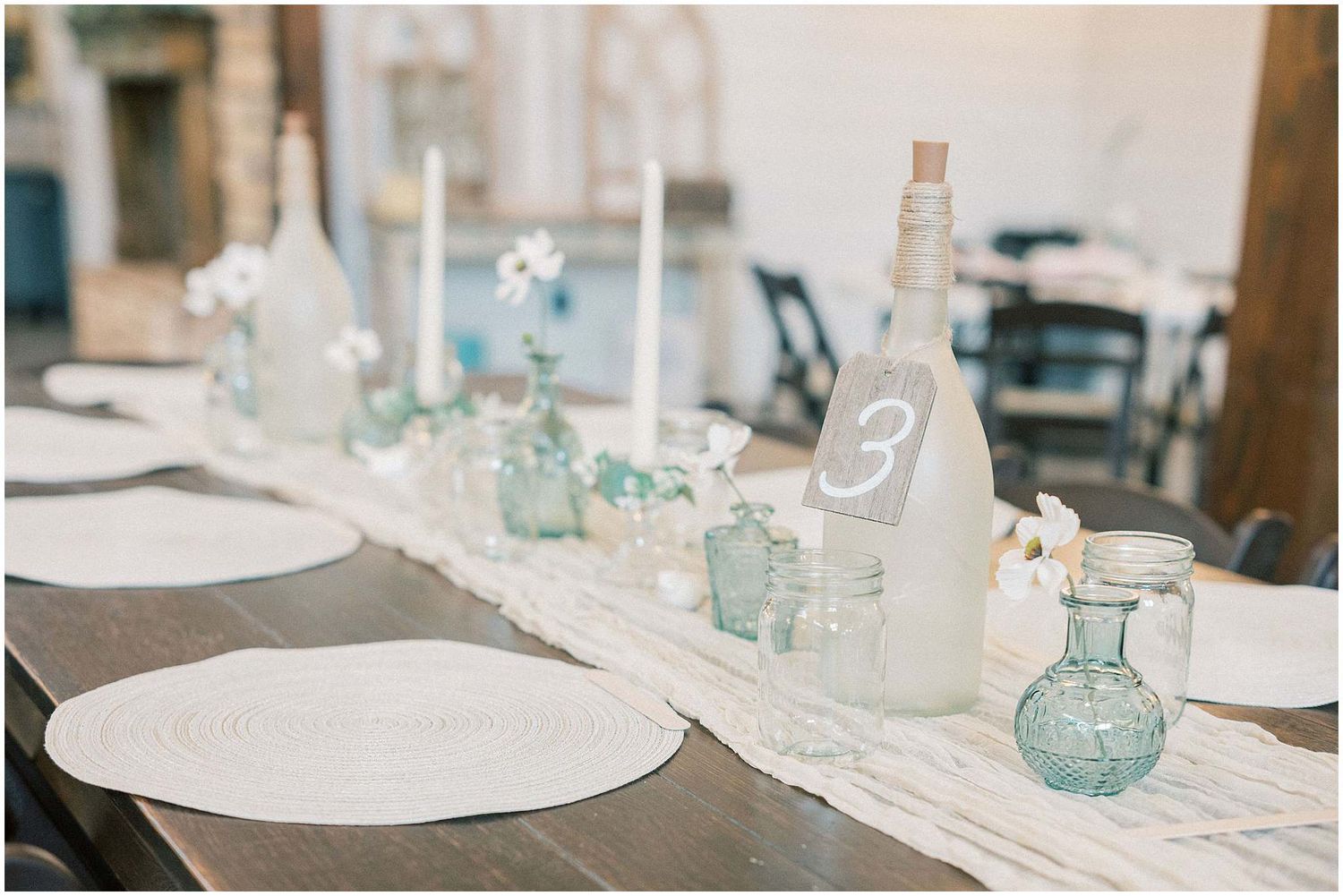 Glass bottles and table settings with soft blue accents create an elegant wedding reception atmosphere.