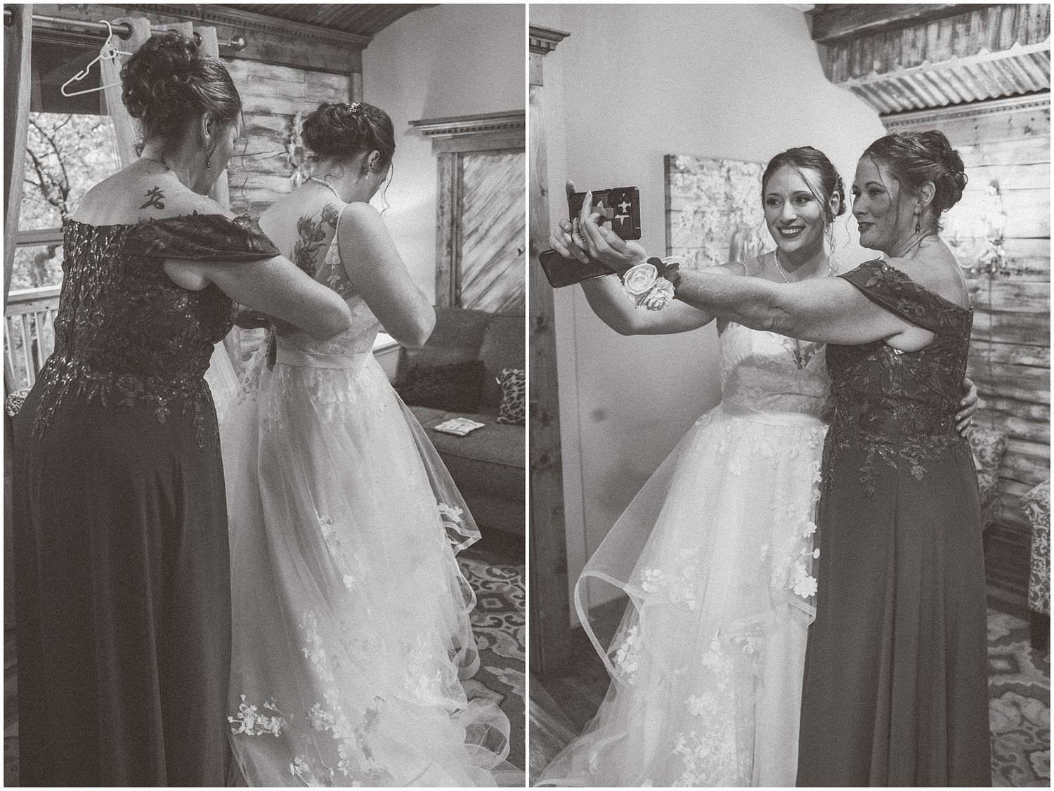 Black and white photo showing two bridal party members helping with wedding dress adjustments in a dressing room.