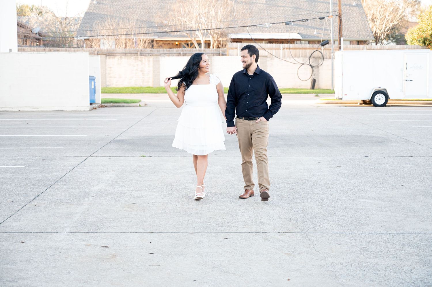 Couple in casual attire walking together in an outdoor setting with buildings in the background.