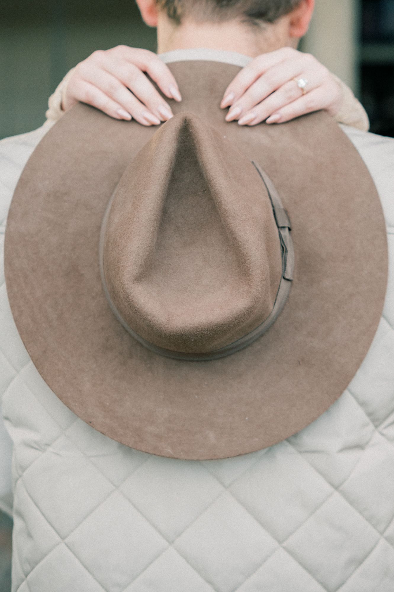 A brown felt western hat displayed on a quilted cream-colored surface.