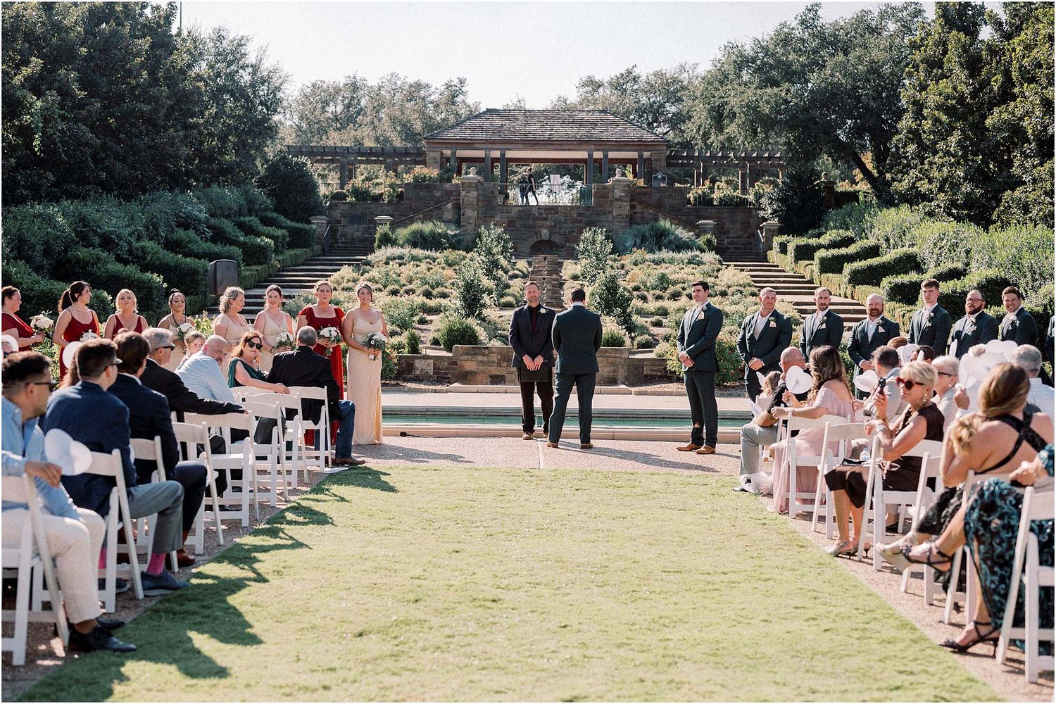 Wedding guests seated in rows for an outdoor garden ceremony.