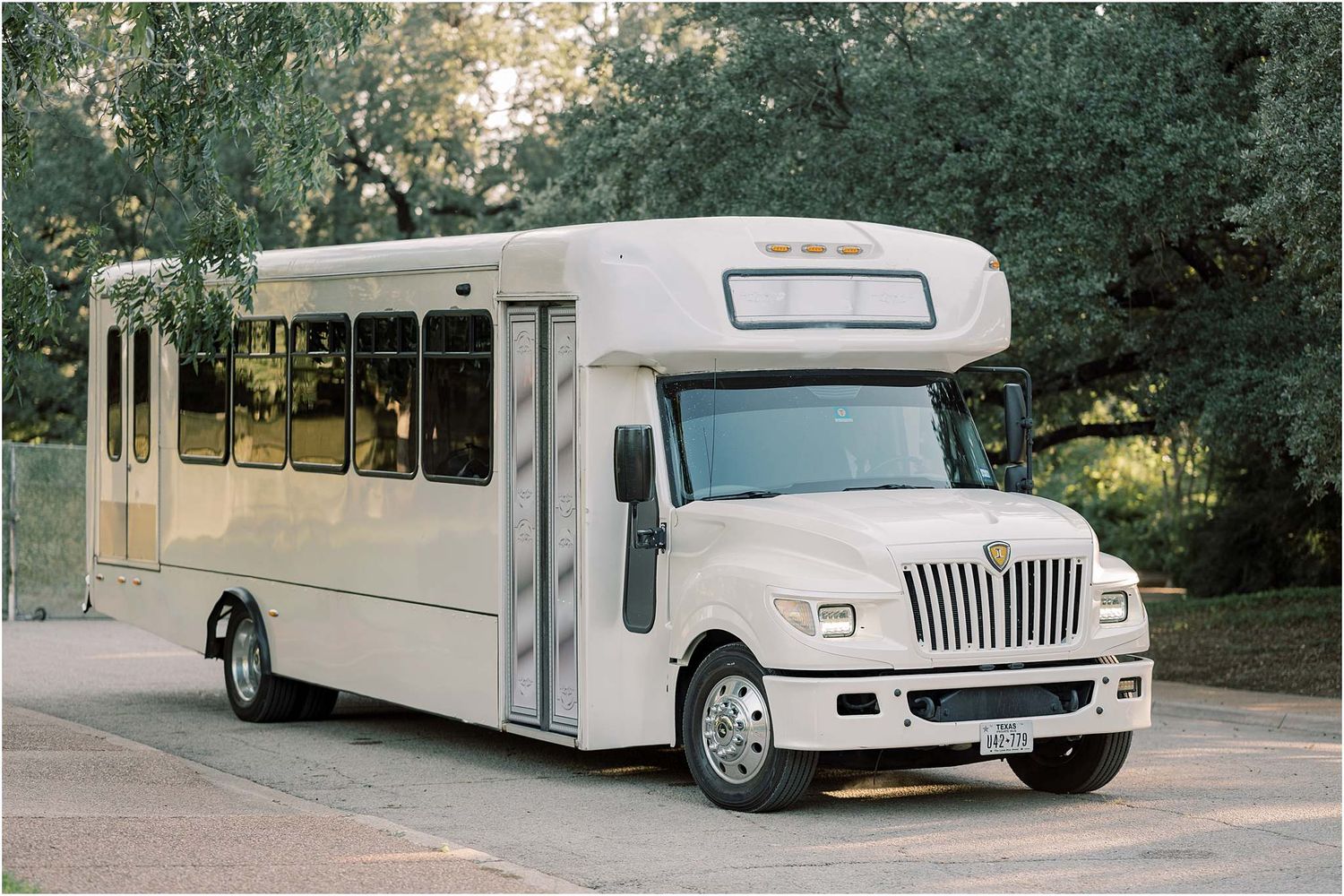 A row of vintage white limousines parked outside on a sunny day.