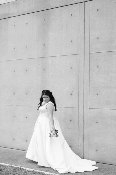 Black and white photo of bride in flowing white gown with train holding bouquet.