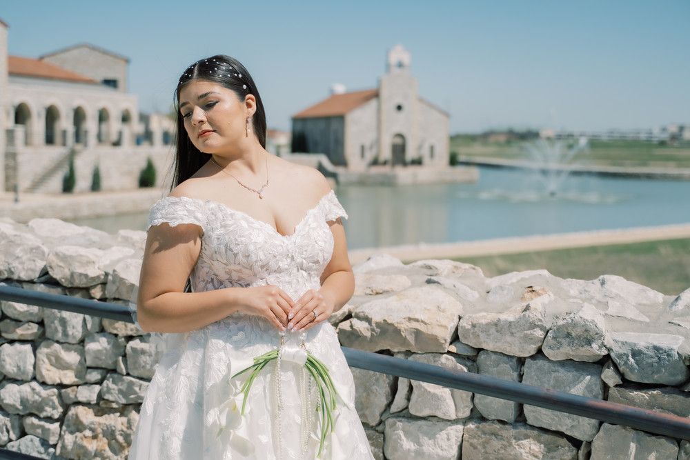 A seaside bridal photoshoot with stone walls and coastal buildings in the background.