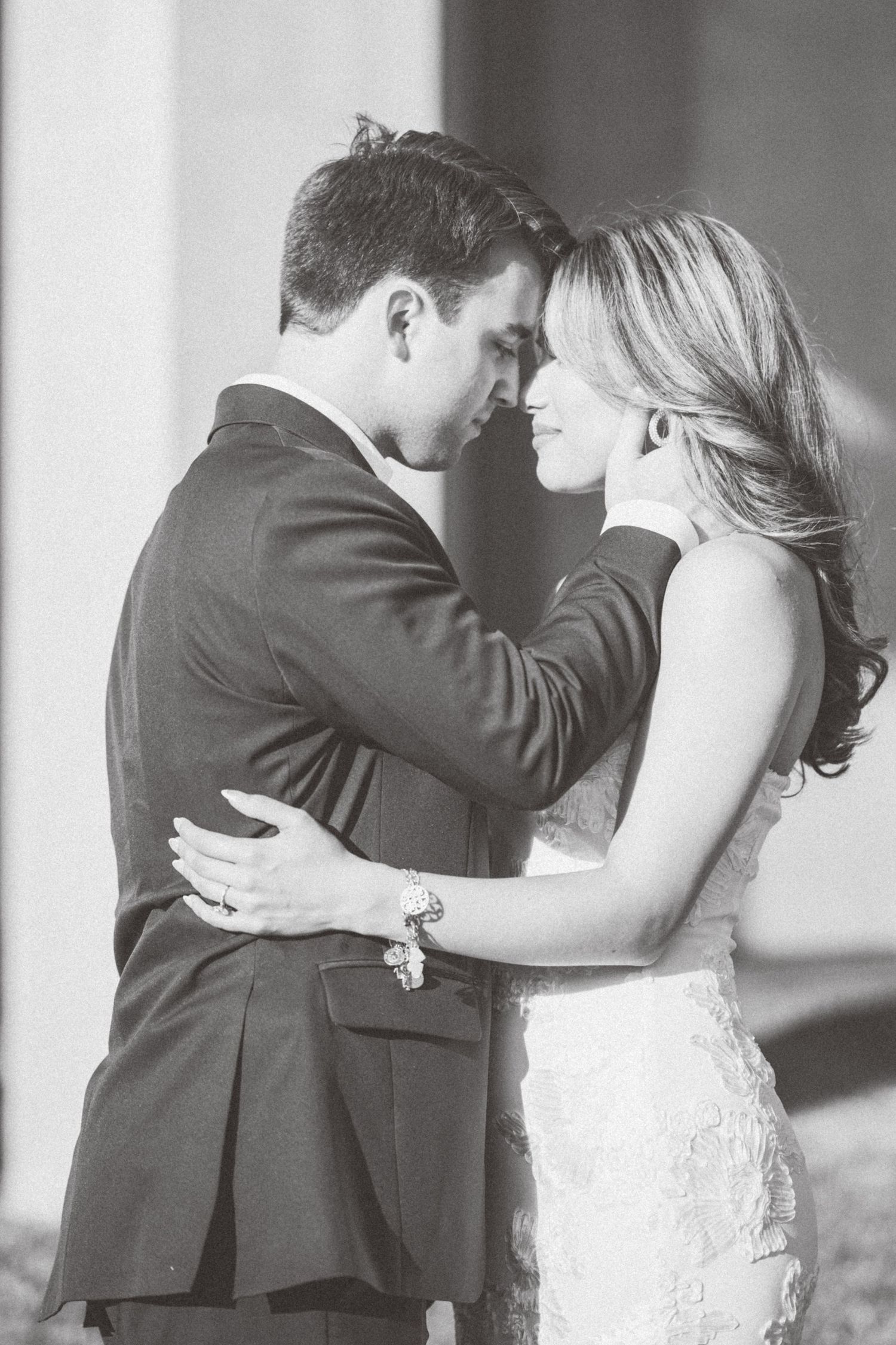 A romantic black and white wedding photo of a couple in formal attire sharing an intimate moment together.
