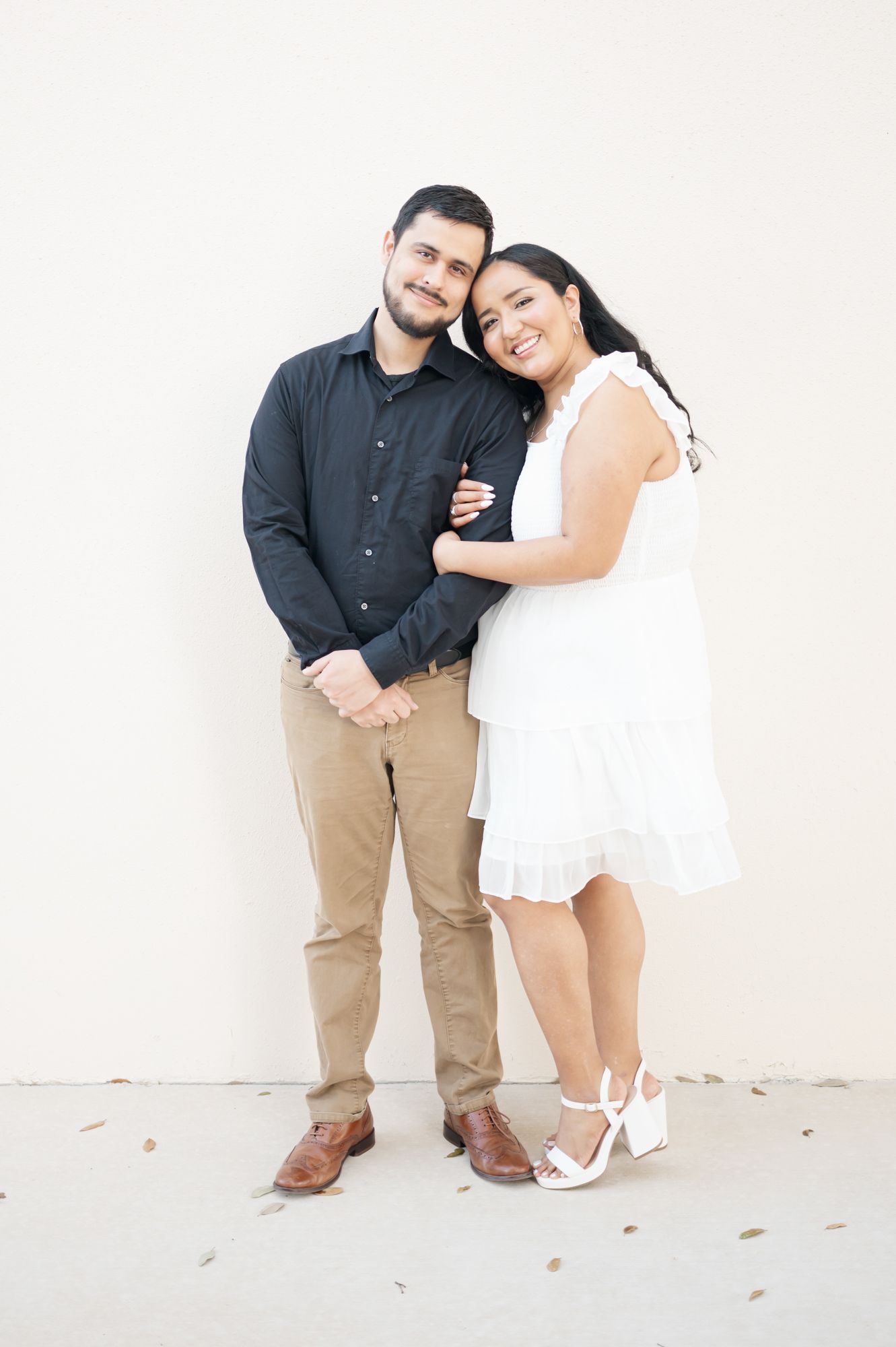 A couple shares an intimate moment while posing against a white backdrop.