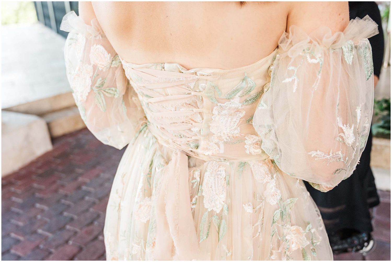 Close-up detail of a blush lace wedding dress with intricate embroidery.