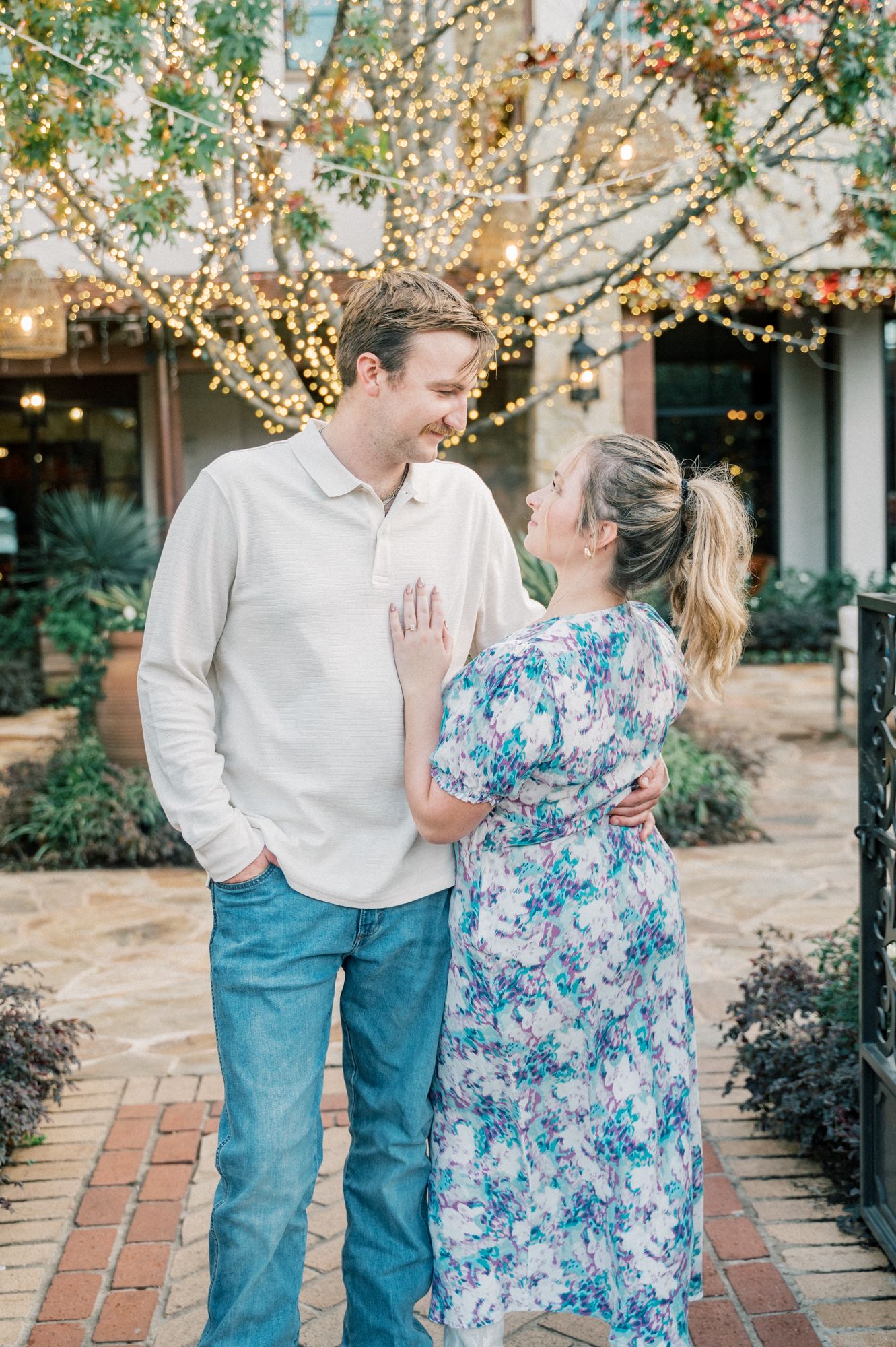 A sweet outdoor photoshoot along a brick pathway with festive holiday lights.