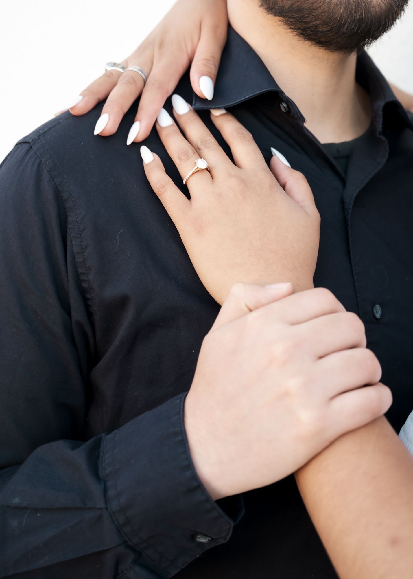 Close-up of hands with wedding rings against a black shirt.