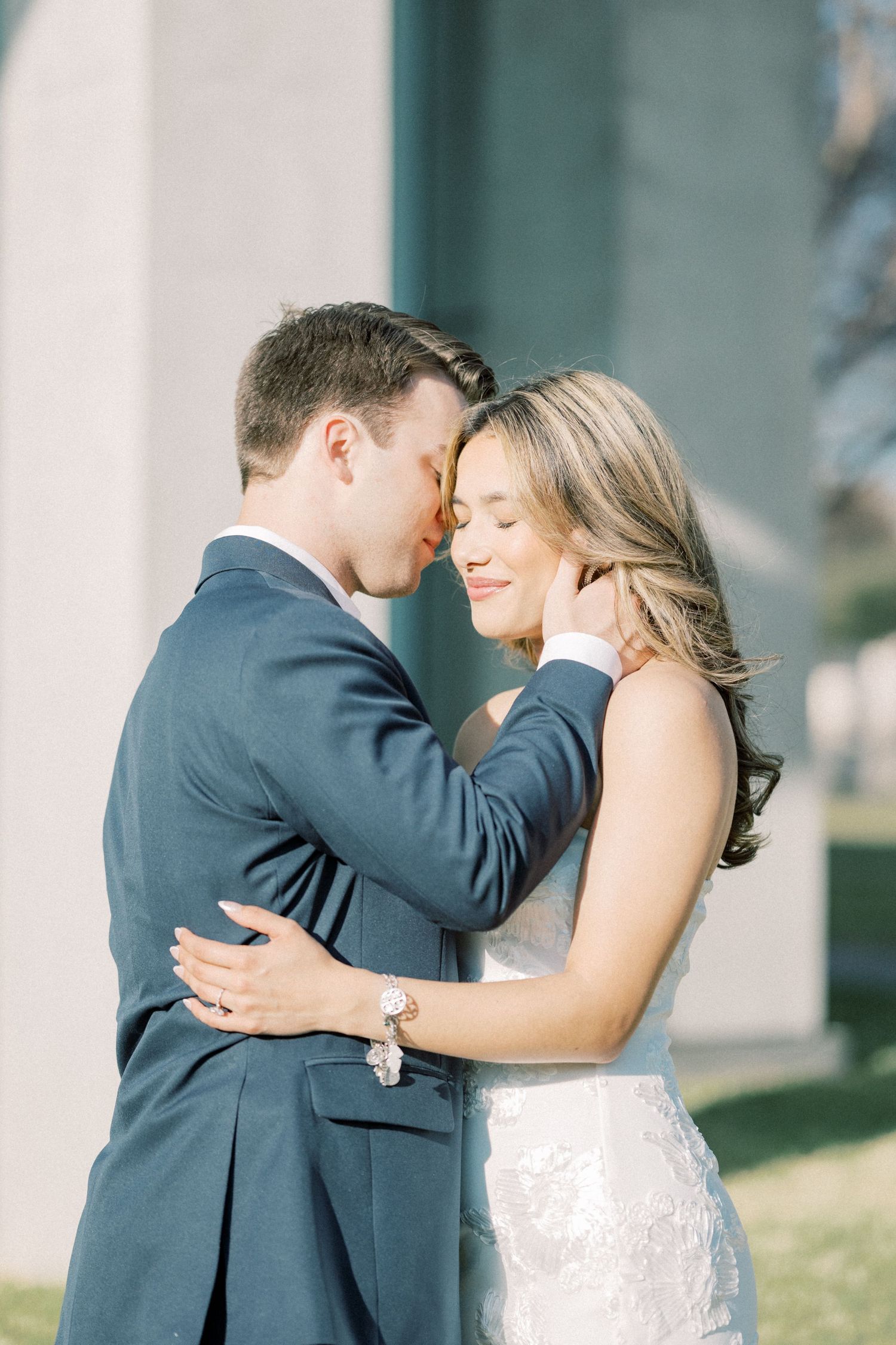 A romantic wedding couple embraces and dances together in an elegant outdoor setting with white columns.