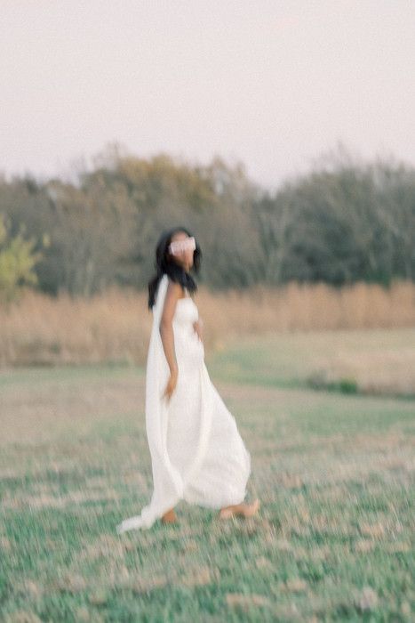 Dreamy motion blur maternity photography in white dress against pastoral backdrop.