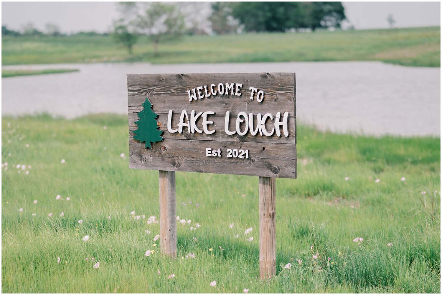 Rustic wooden welcome signs mark the entrance to a lakeside wedding venue.