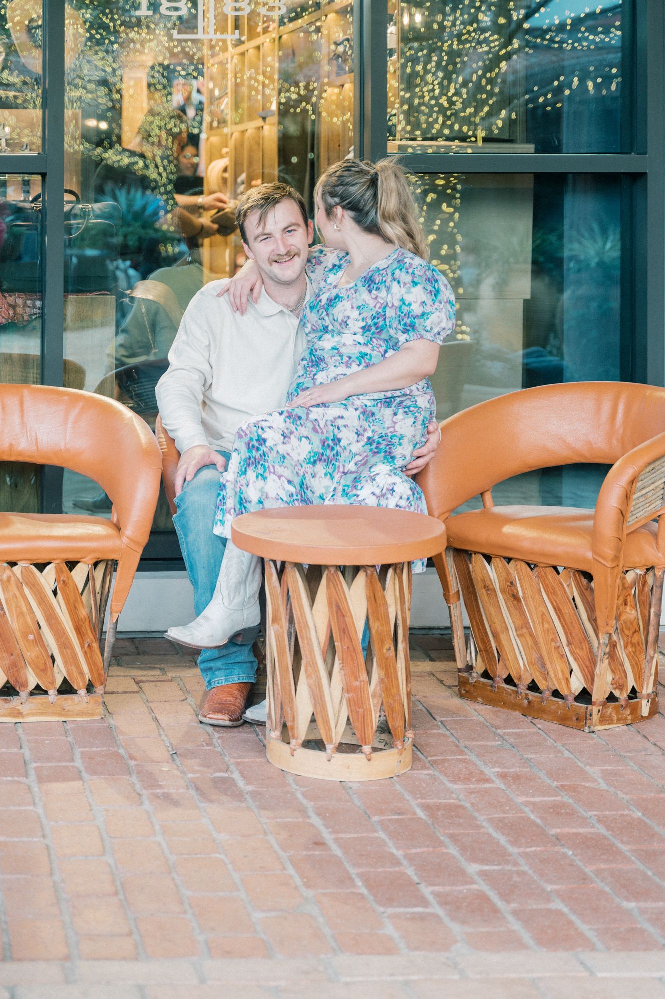Intimate moment shared on terrace with traditional leather equipale chairs and string lights.