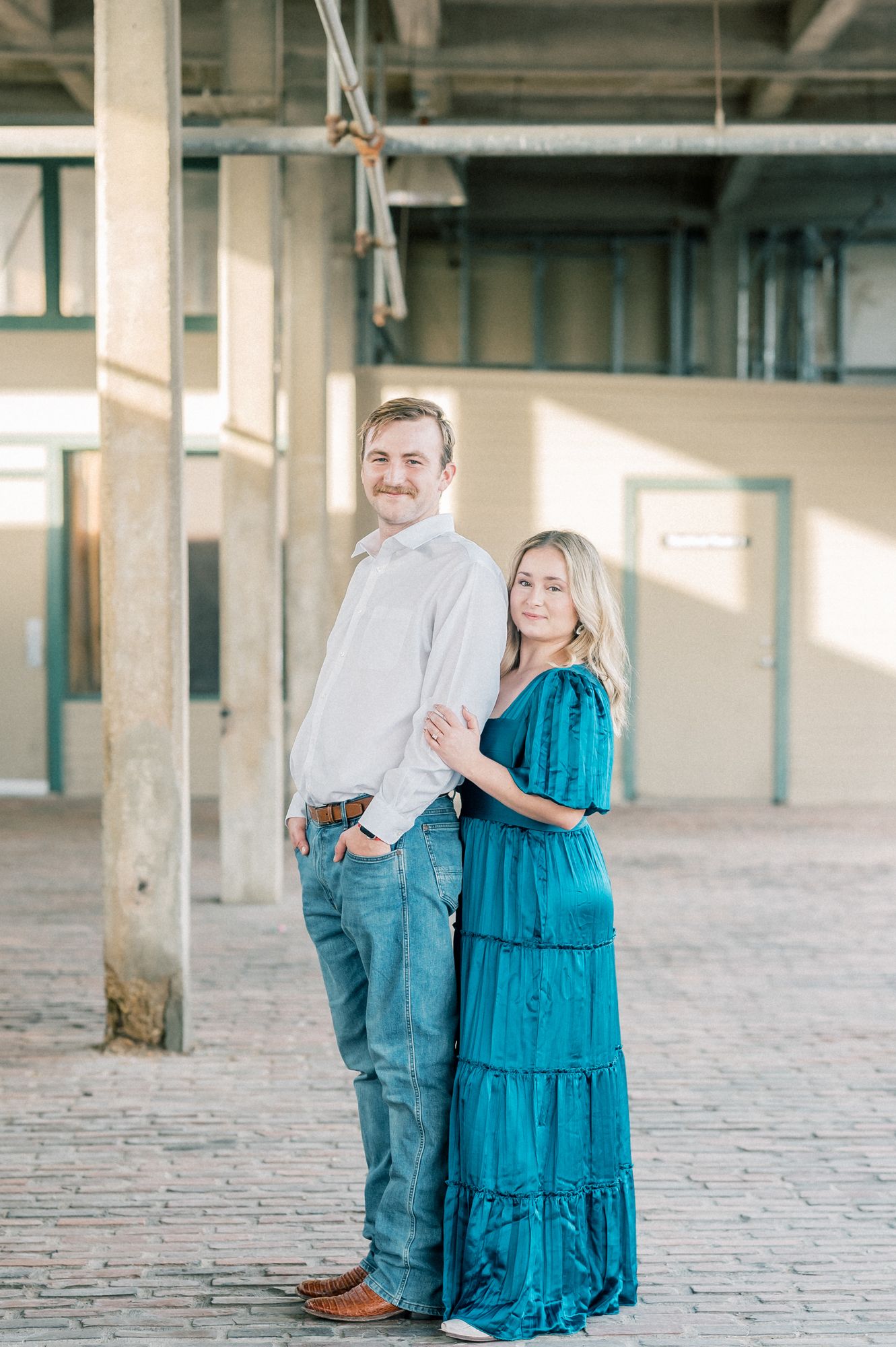 A romantic portrait in a warehouse setting with a couple wearing coordinating outfits of blue and white.