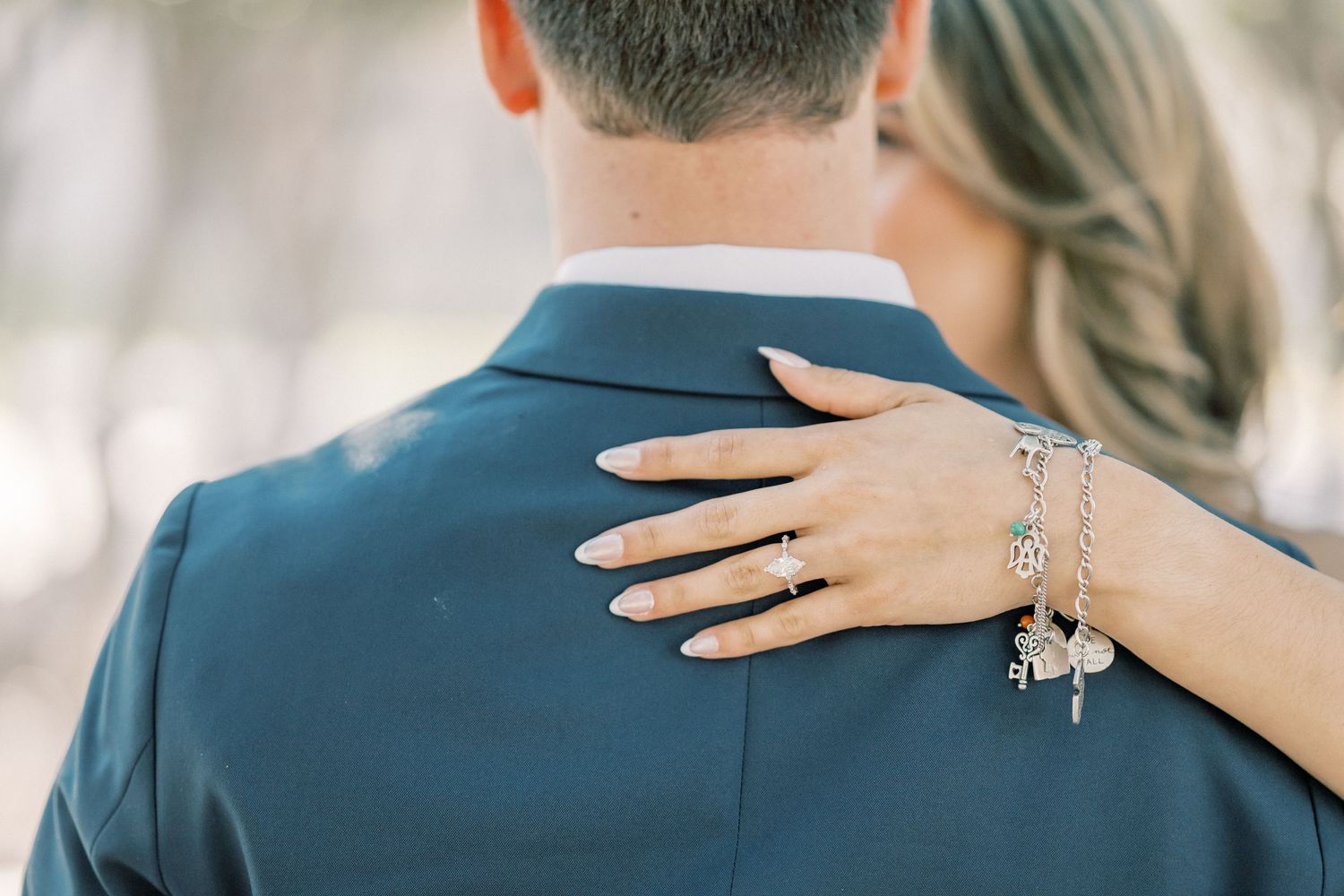 A couple in elegant wedding attire embrace in a romantic outdoor setting with soft natural lighting.