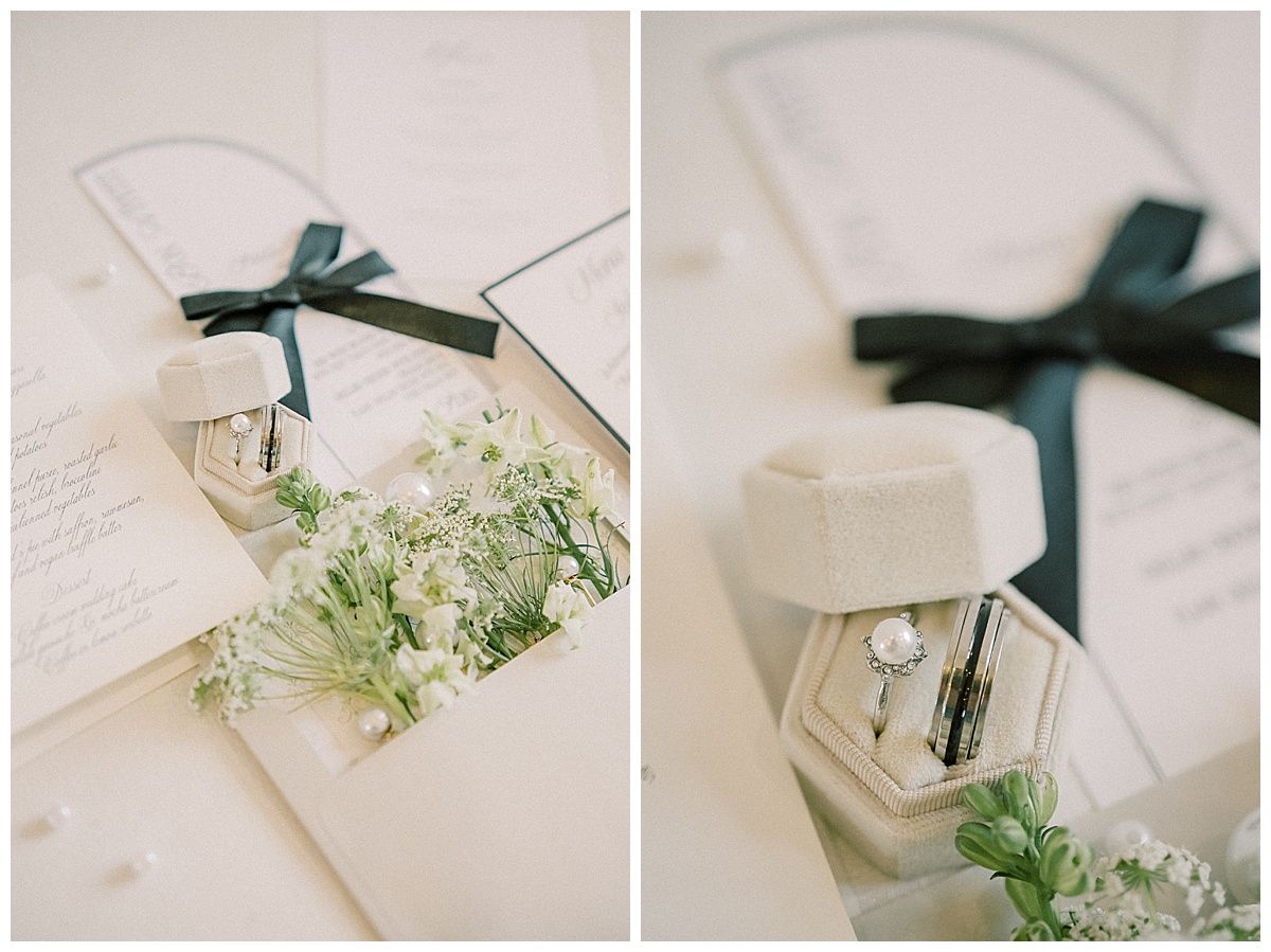 A series of cream-colored wedding invitations with dark green ribbons and delicate baby's breath flowers arranged on a white surface.