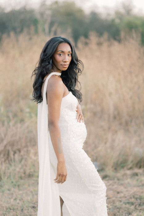 Stunning white gown with delicate details photographed in natural outdoor setting.
