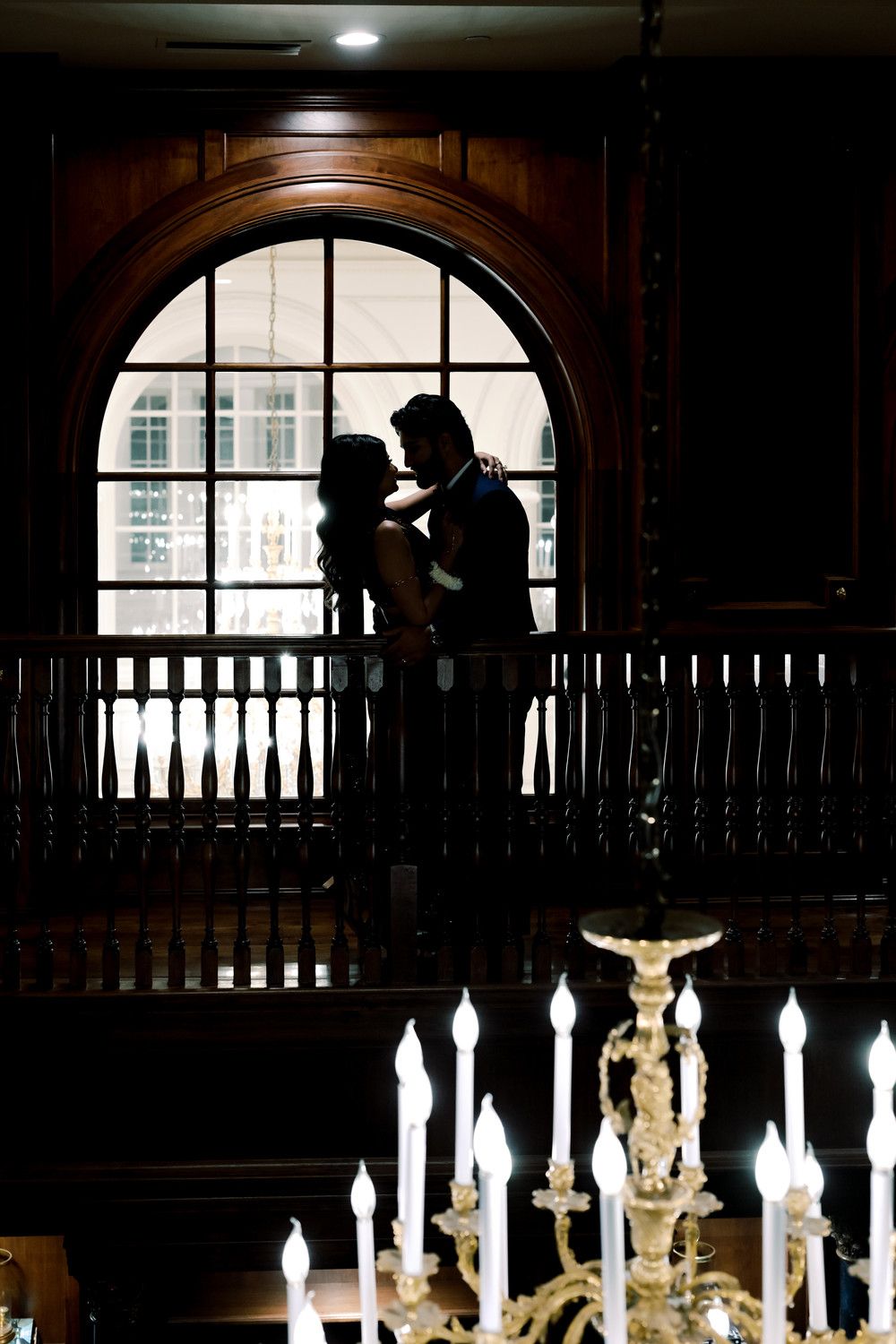 Dramatic silhouette scene with illuminated candles and arched windows in dark interior.