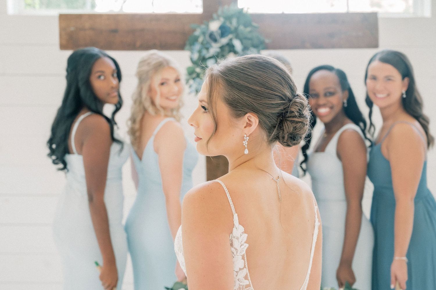 Bridal party wearing powder blue dresses poses together in an elegant white space.