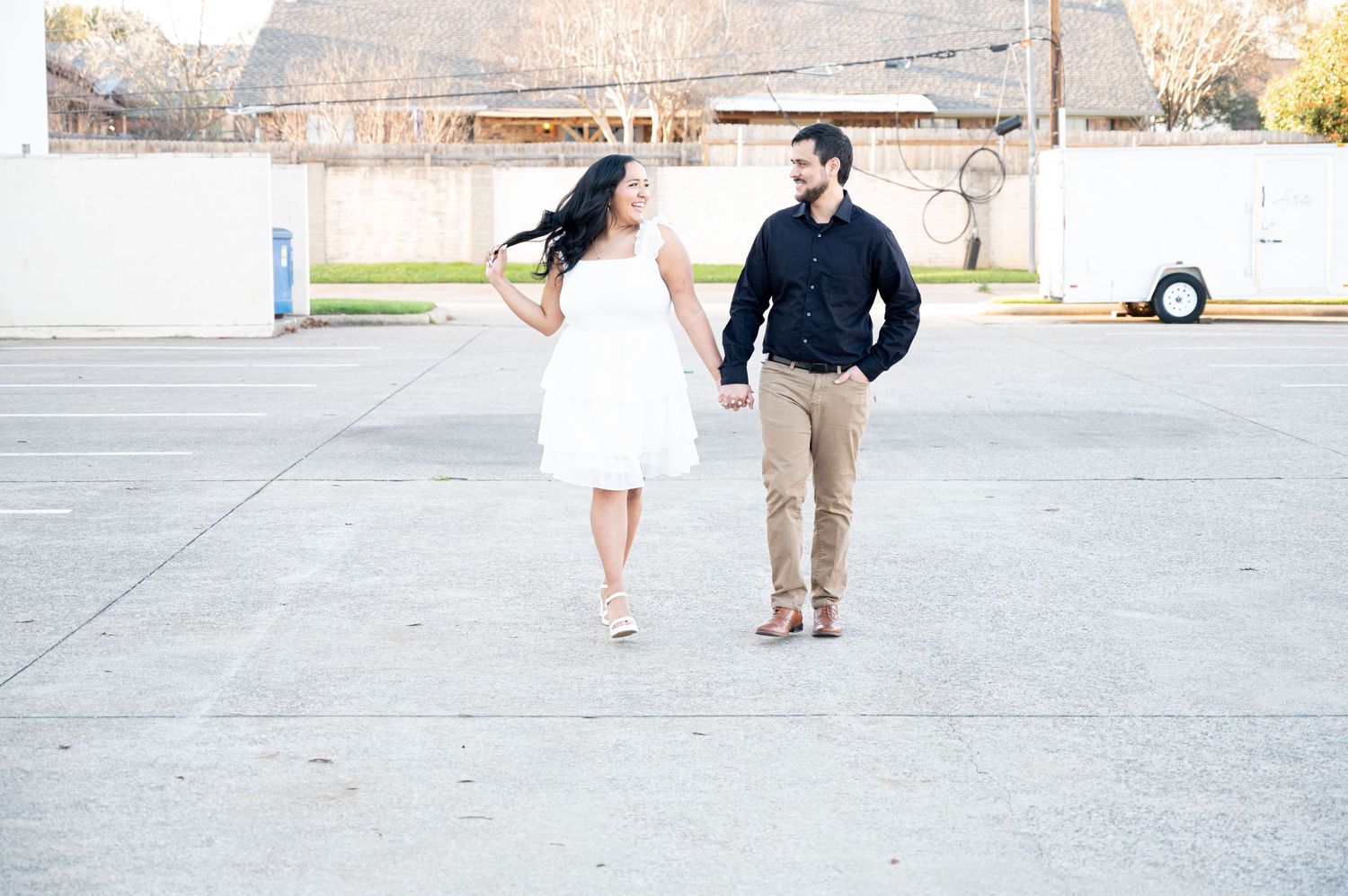 A couple dances playfully against a pink wall wearing black and white outfits.