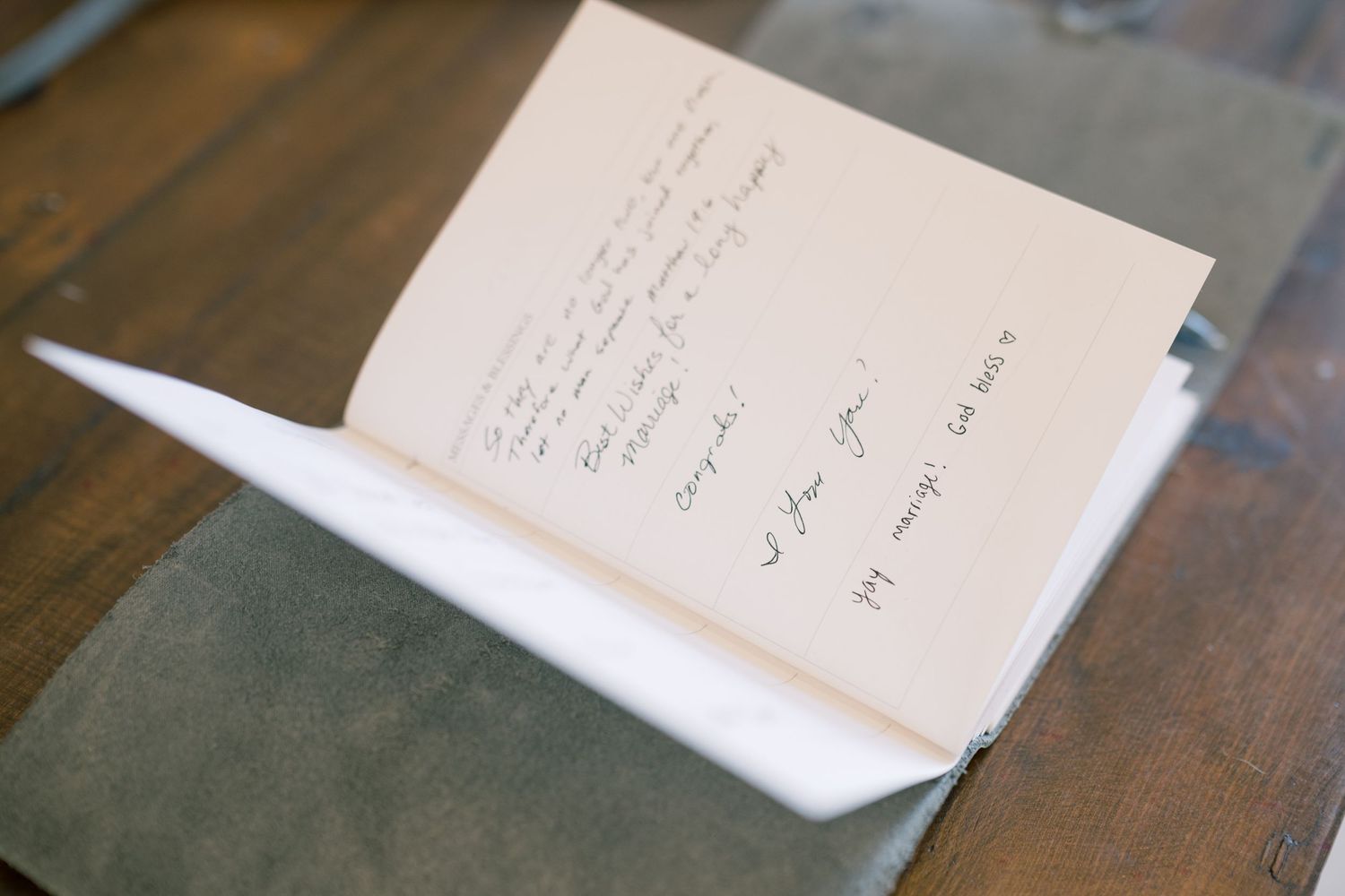 Handwritten note inside a card placed on a gray envelope on wood table.