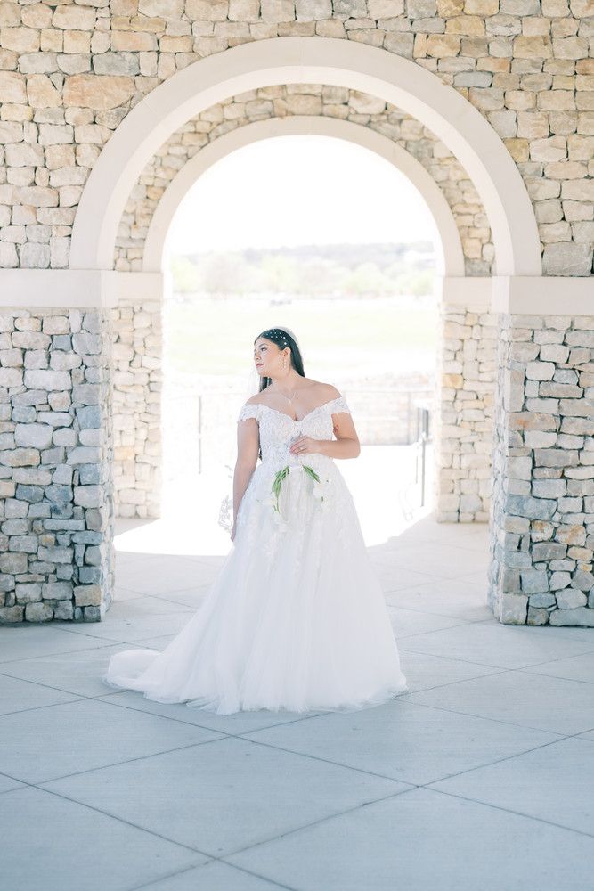 Elegant bridal portraits under stone archways with a flowing white wedding gown against a light backdrop.
