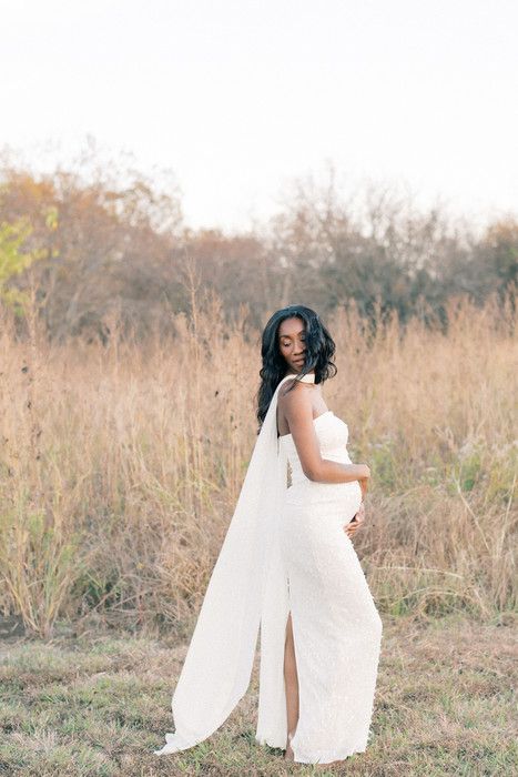 Ethereal maternity photoshoot in a golden field with flowing white fabric and natural sunlight.