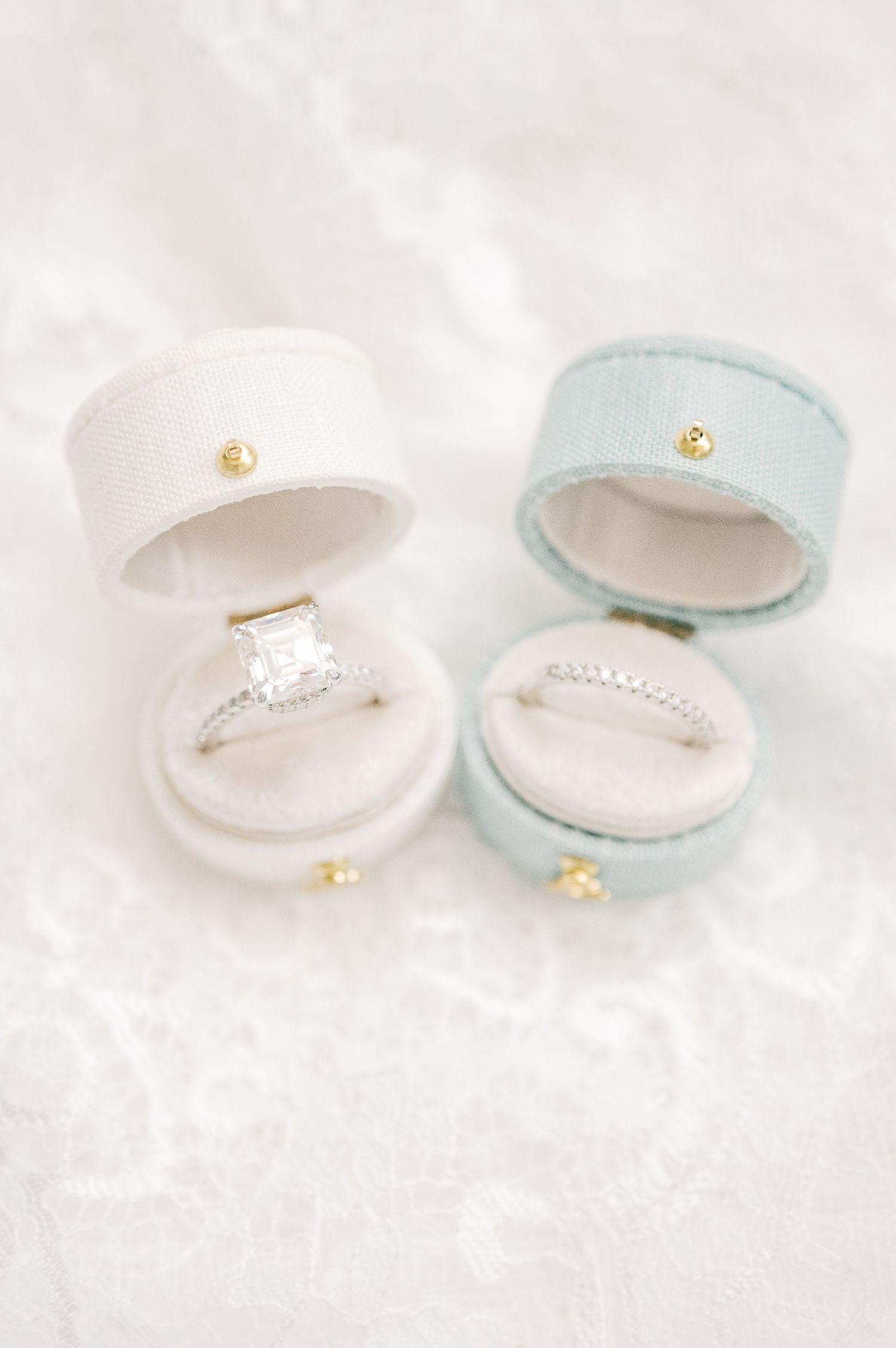 Two elegant wedding rings displayed in open velvet ring boxes, one white with a diamond solitaire and one blue with a band.